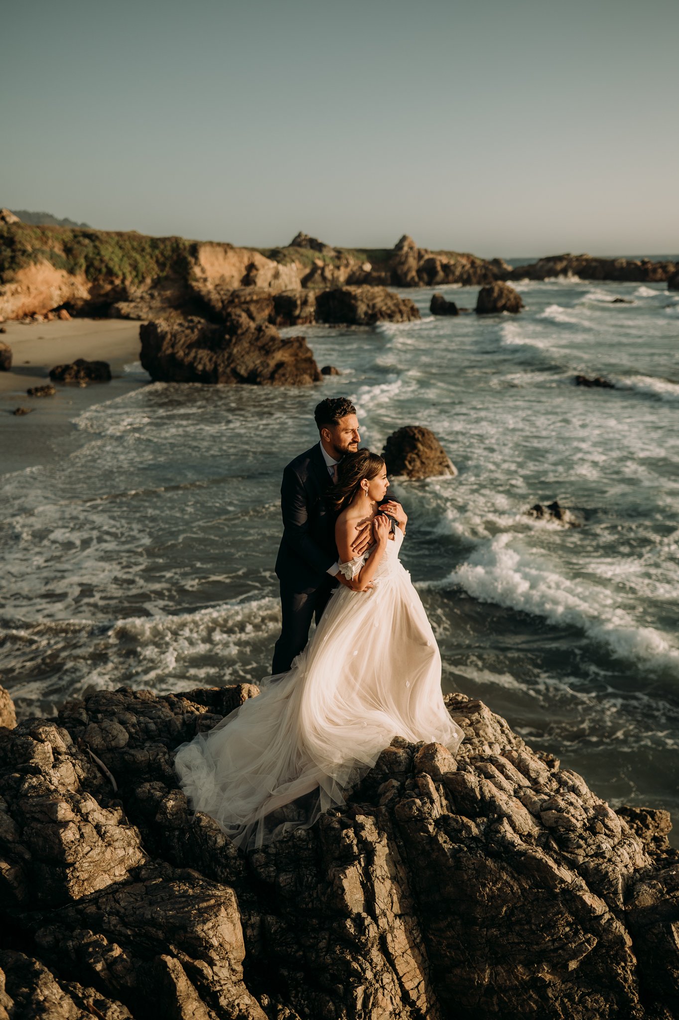 Elopement in Big Sur bride and groom standing cliffside at sunset 