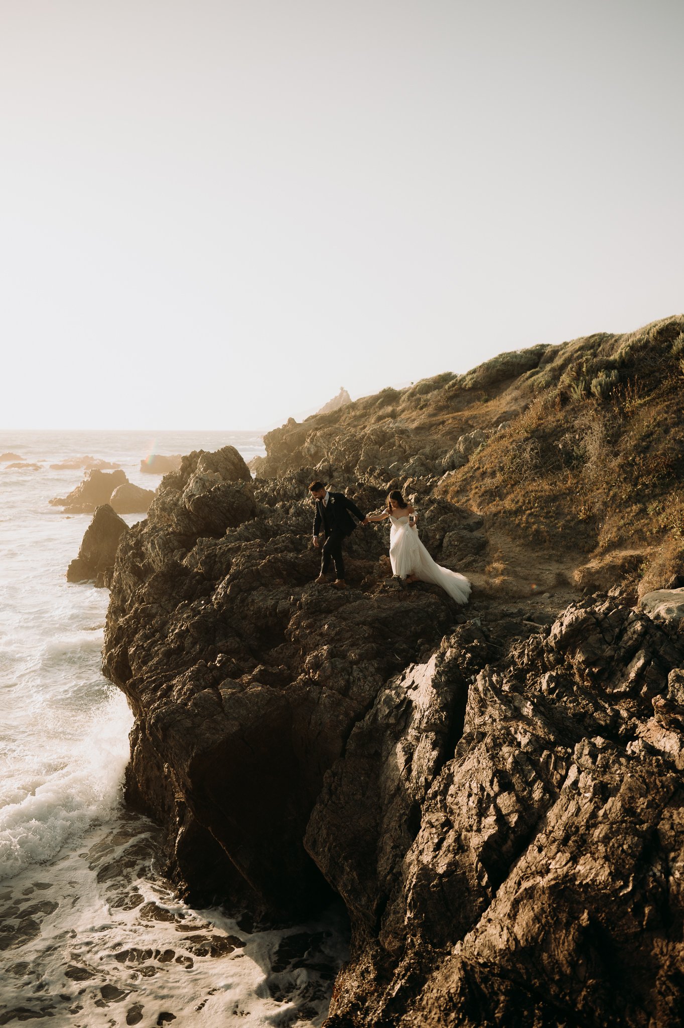 Birde and groom posing on cliff in Big Sur California