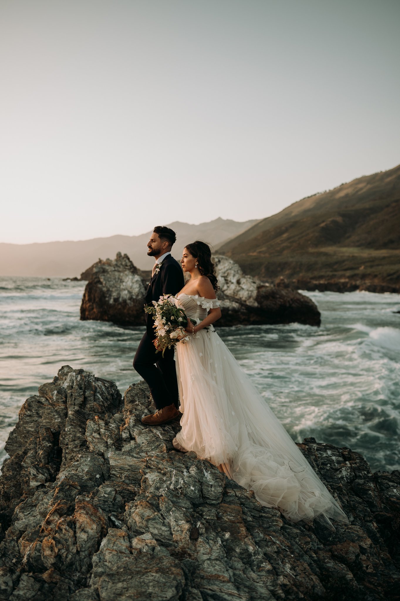 bride and groom standing side by side watching sunset in Big Sur