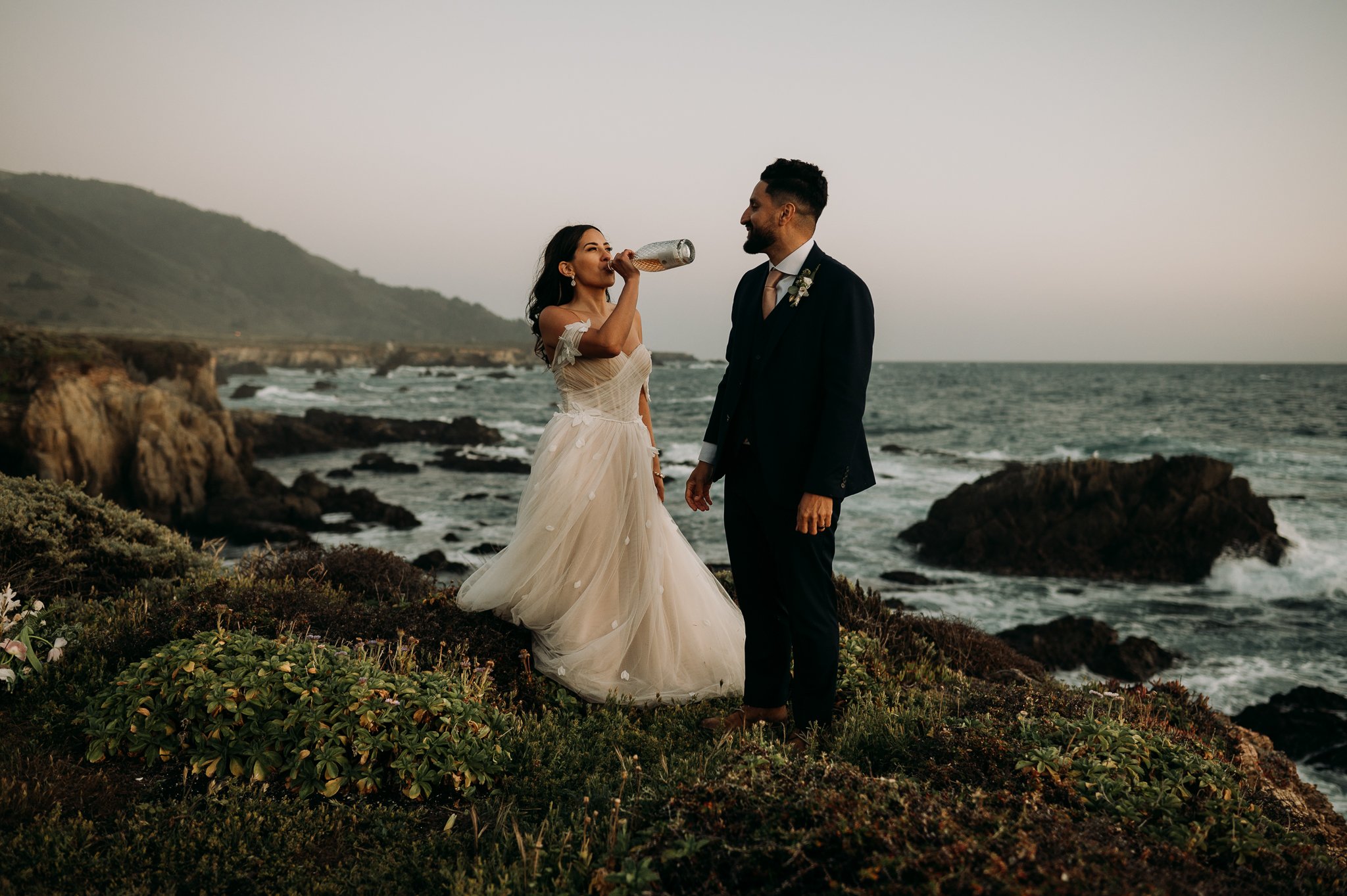 bride and groom drinking champagne cliffside in Big Sur
