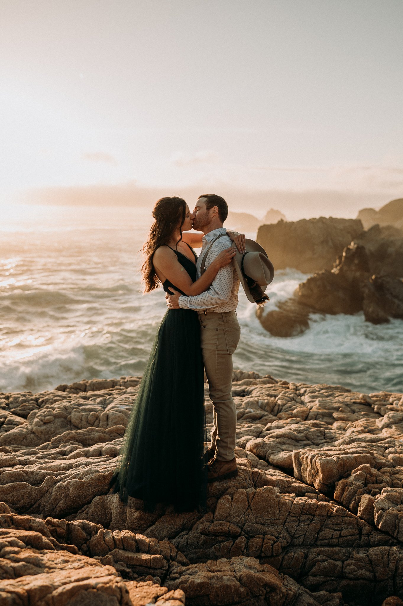 Newly engaged couple hugging cliffside in Big Sur California