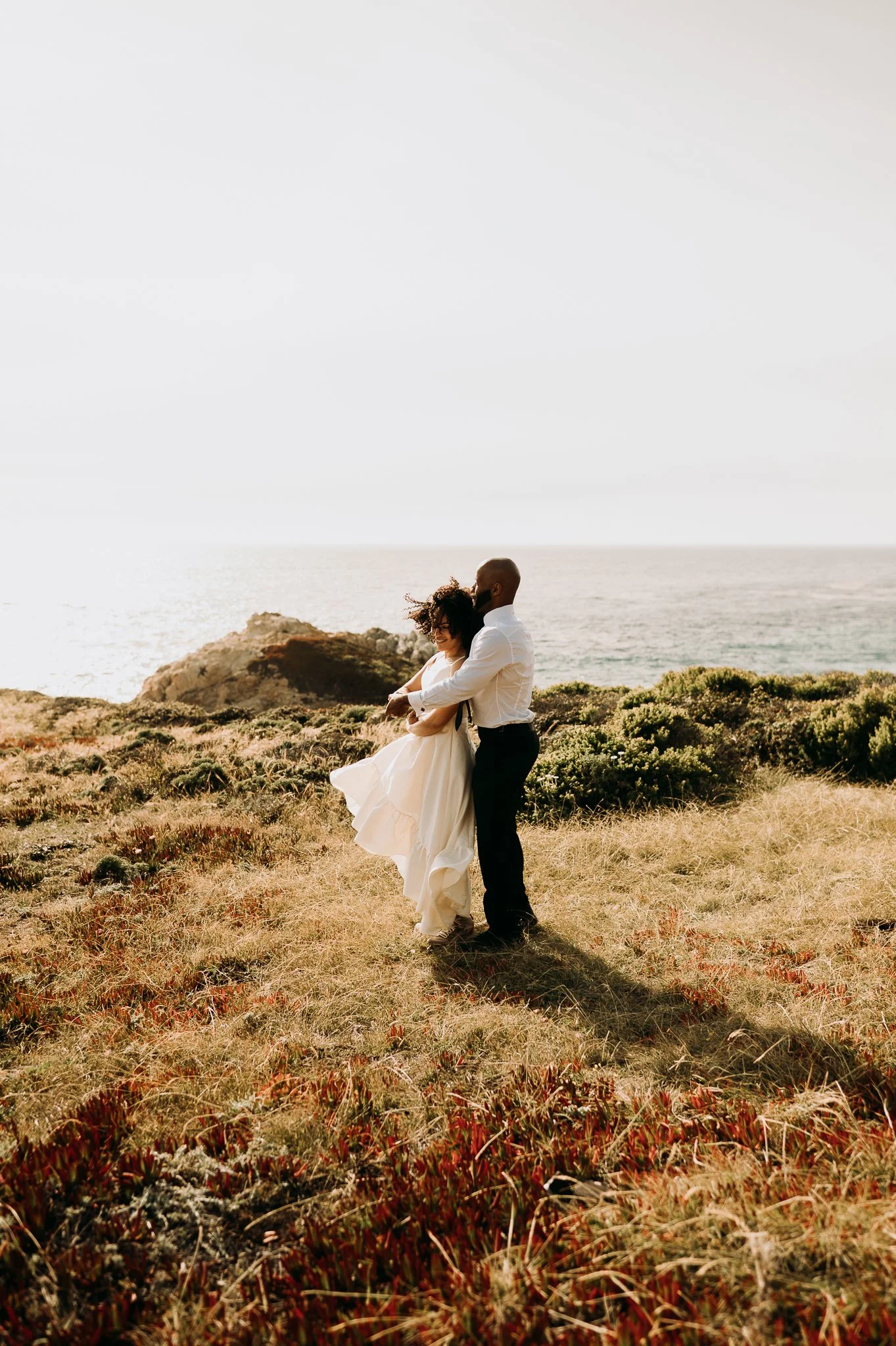 Elopement couple dancing on grassy area above Pacific Ocean Big Sur