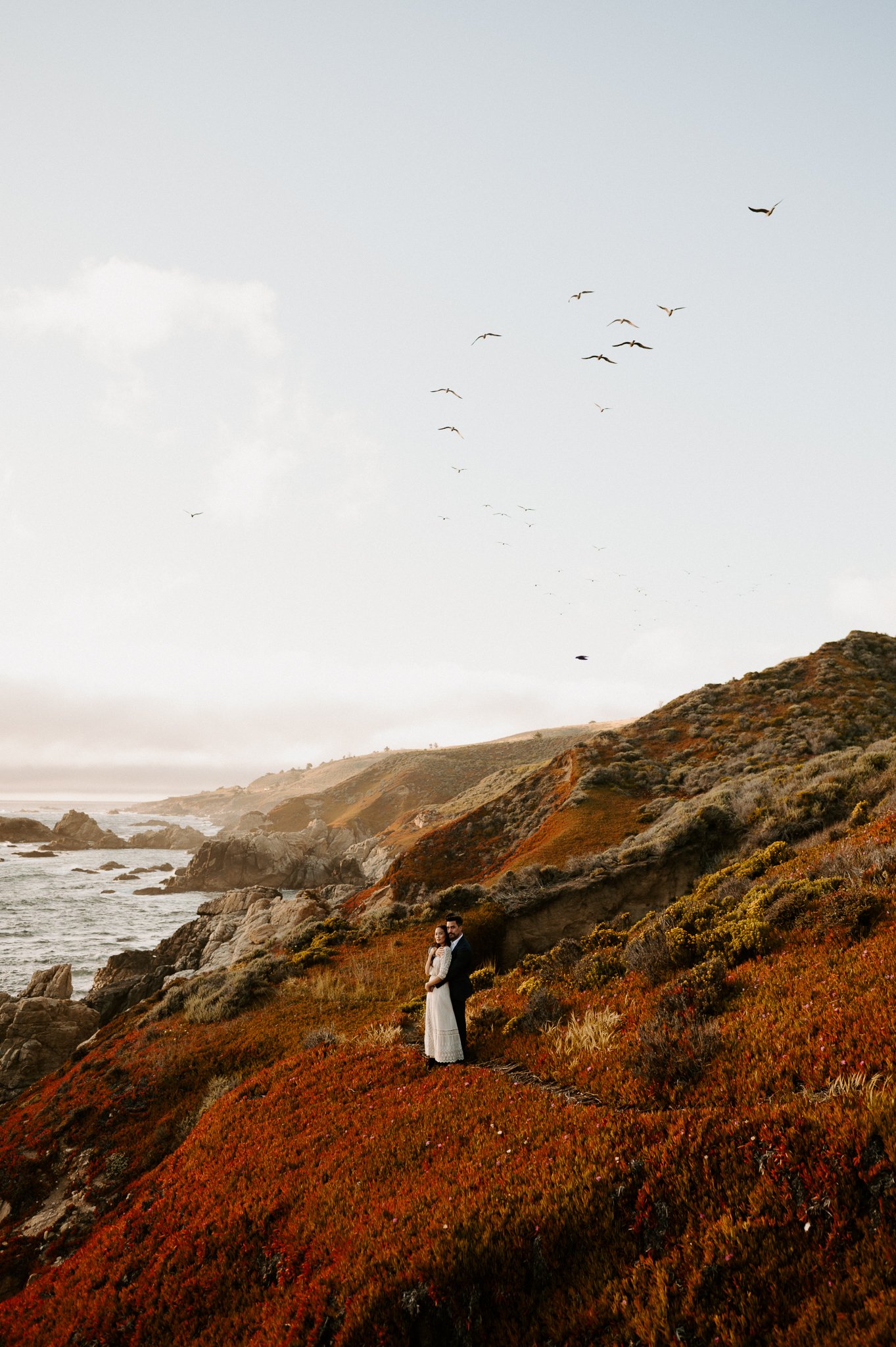 newly engaged couple sharing intimate moment on cliff in Big Sur