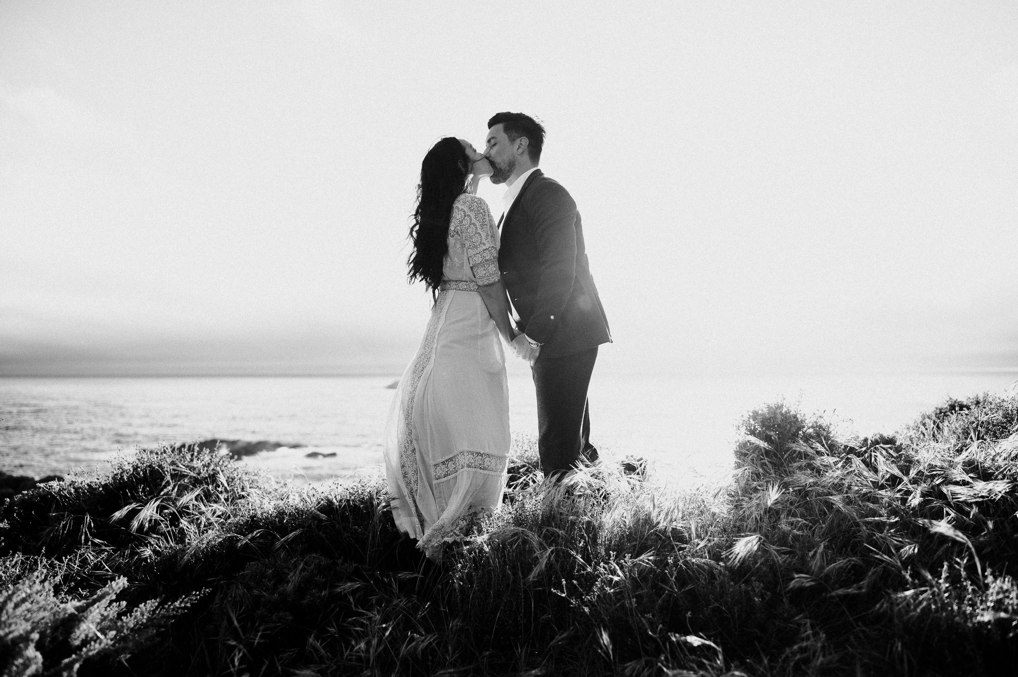 black and white shot of couple kissing with Pacific Ocean in background