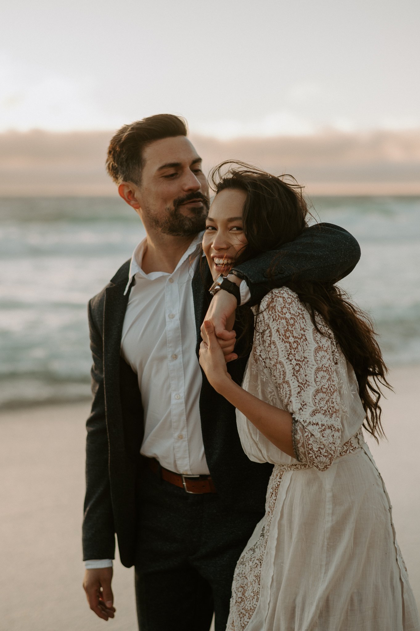 Newly engaged couple walking on beach Big Sur