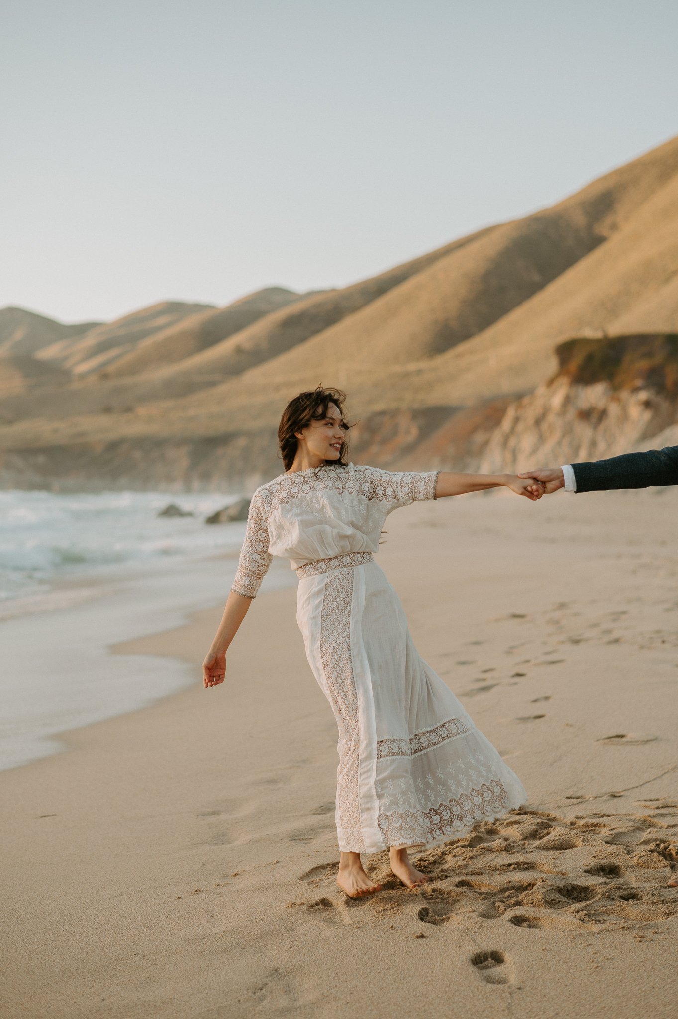 newly engaged woman holding her fiancé's hand he is not shown on beach in Big Sur