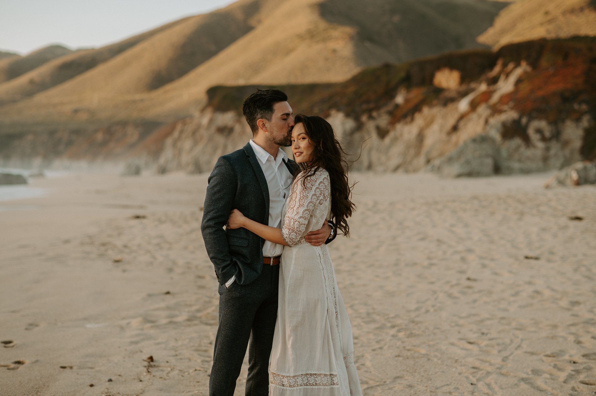 Newly engaged couple hugging on beach Big Sur