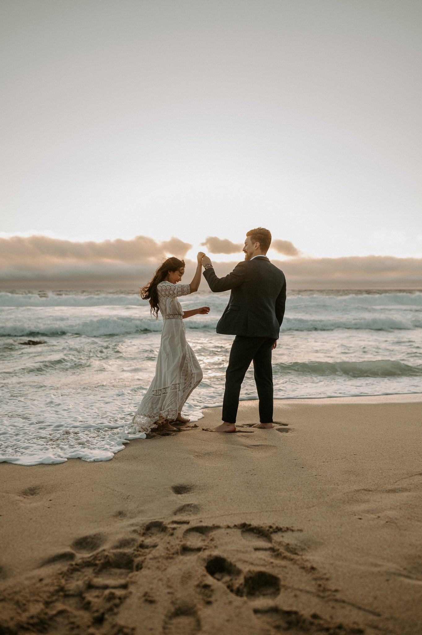 engagement couple dancing in water on beach in Big Sur
