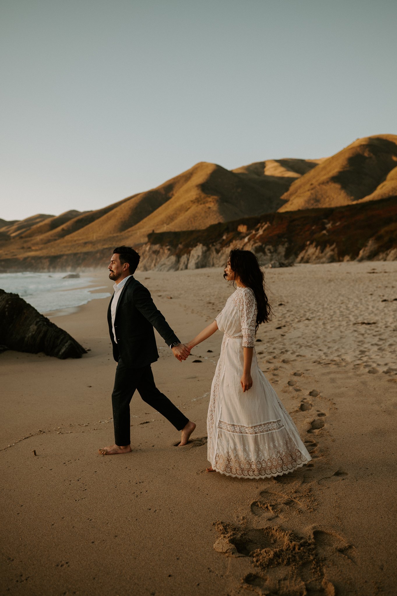 newly engaged couple walking on beach in Big Sur hand in hand
