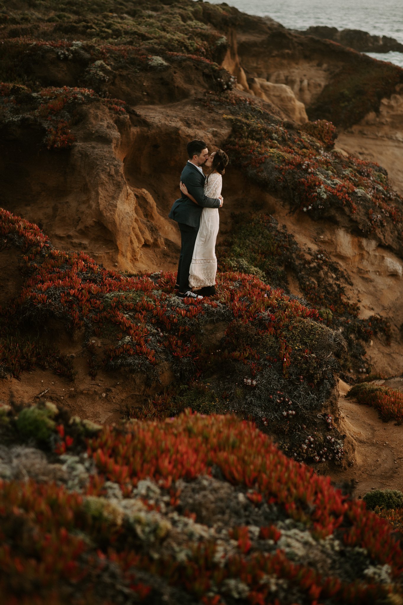 newly engaged couple standing on cliff in Big Sur  sharing a kiss