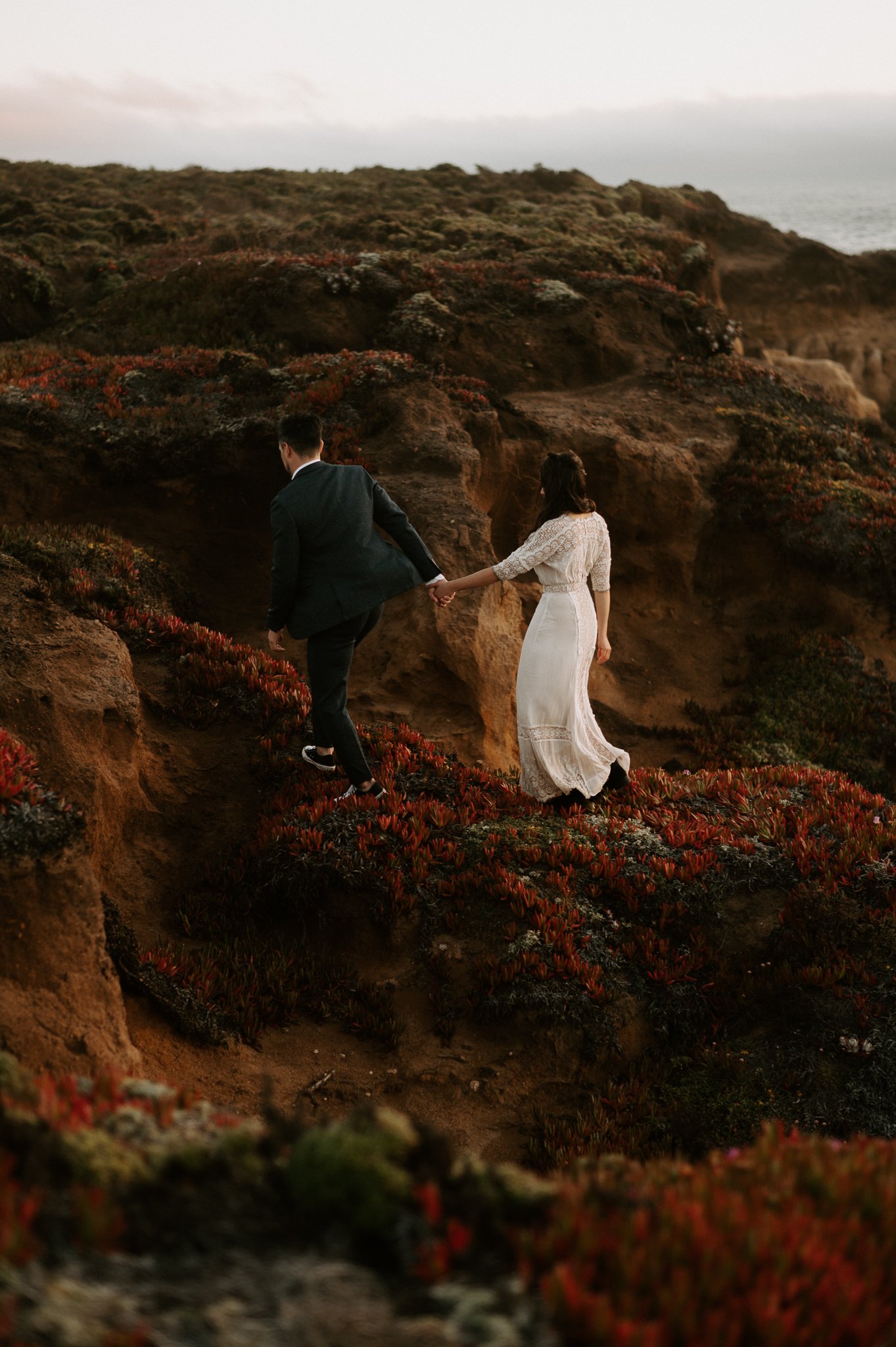 newly engaged couple walking holding hands on cliff in Big Sur 