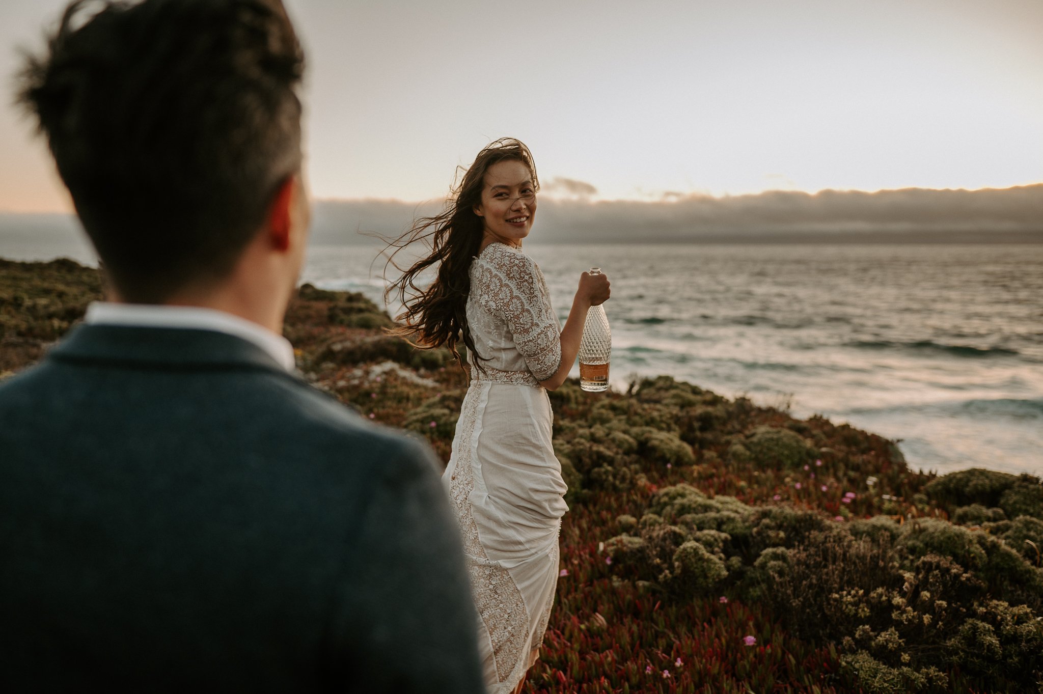 newly engaged couple standing on cliff in Big Sur sharing champagne 