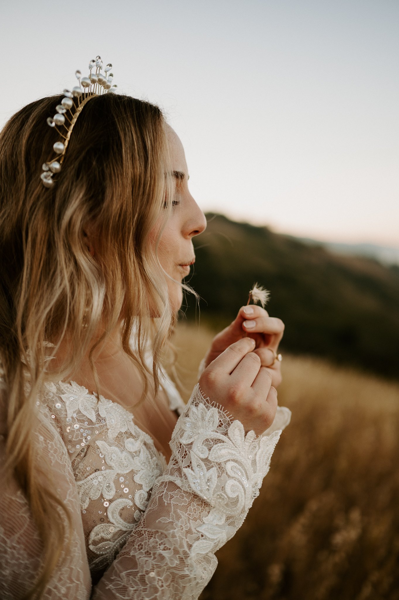 Big Sur brides upper body as she is blowing on a dandelion