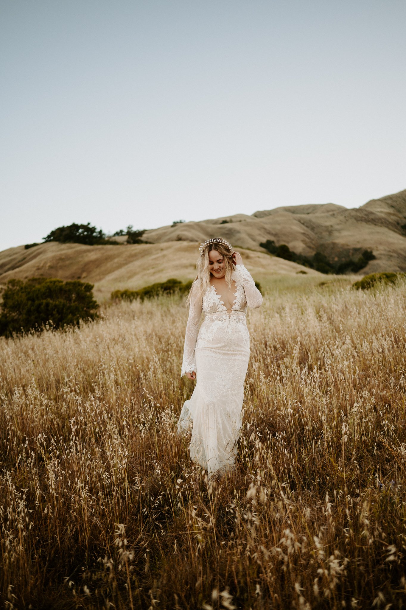 Bride in wedding dress walking in tall brown grasses in Big Sur