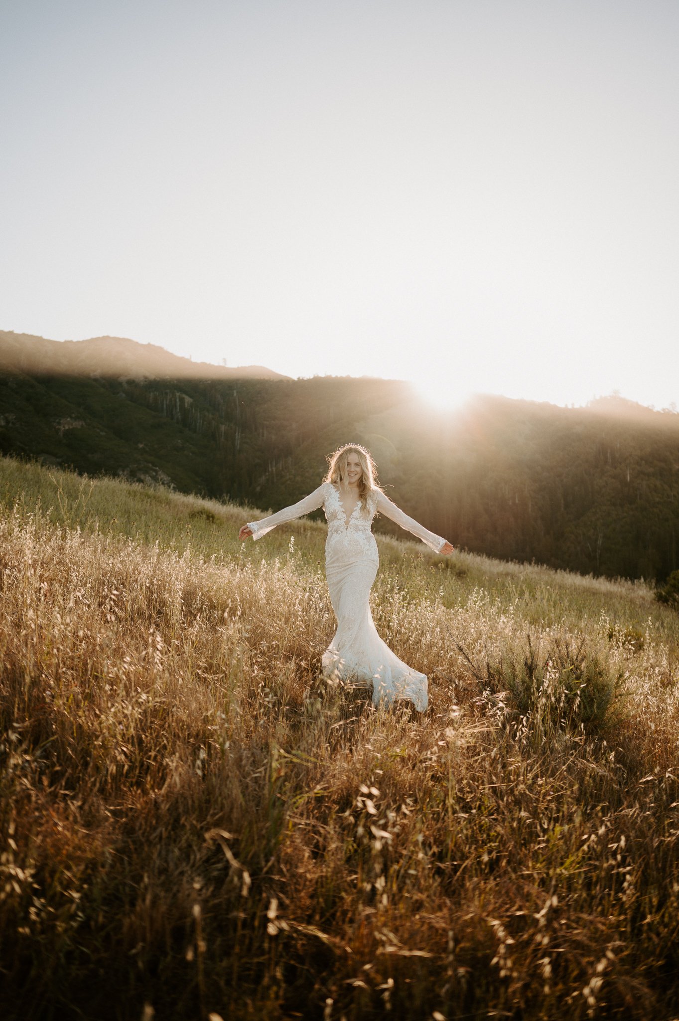 Bride in tall grasses of Big Sur posing with arms out at her side