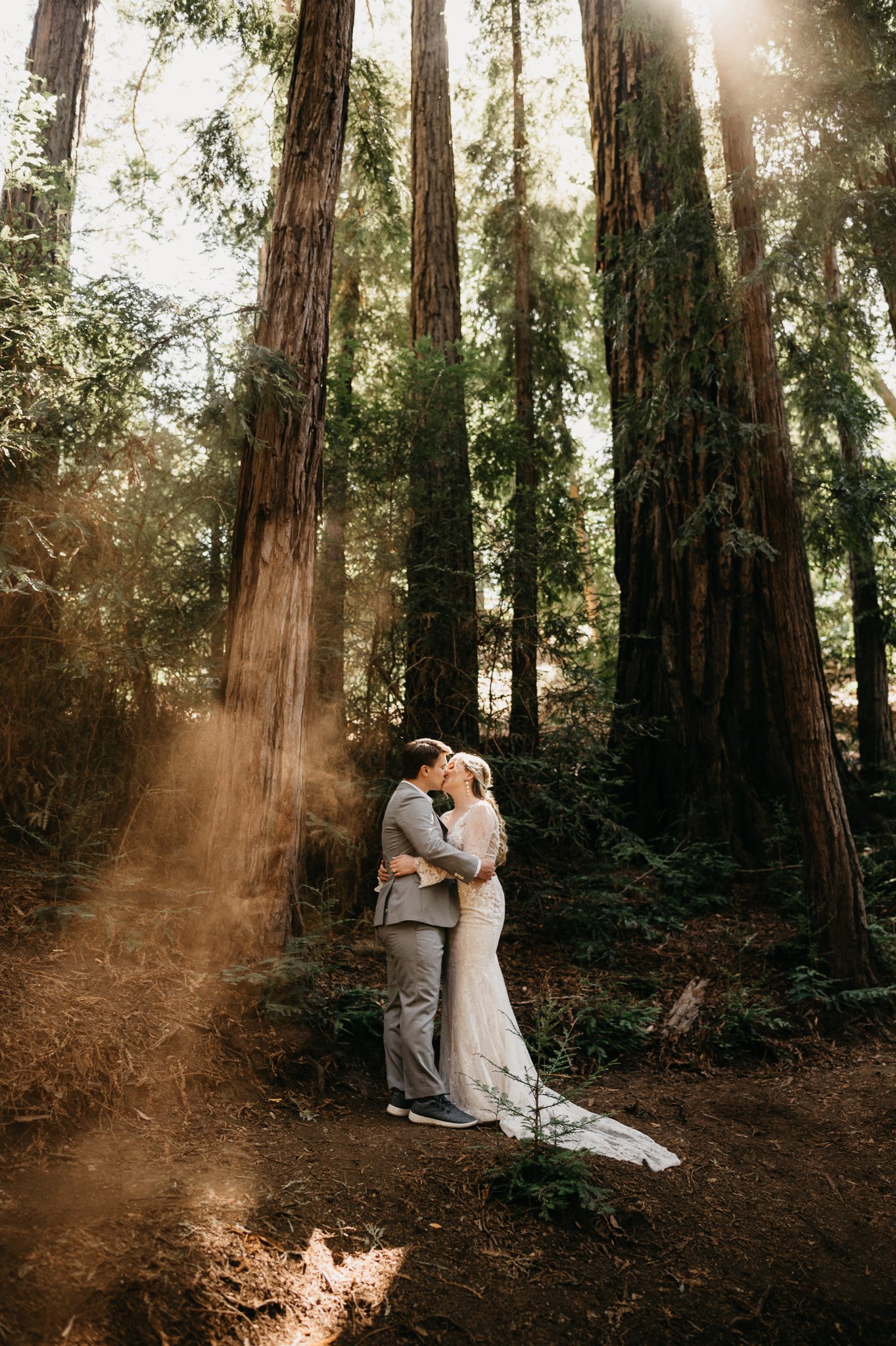 Bride and groom in forest of Big Sur kissing under the tall redwoods