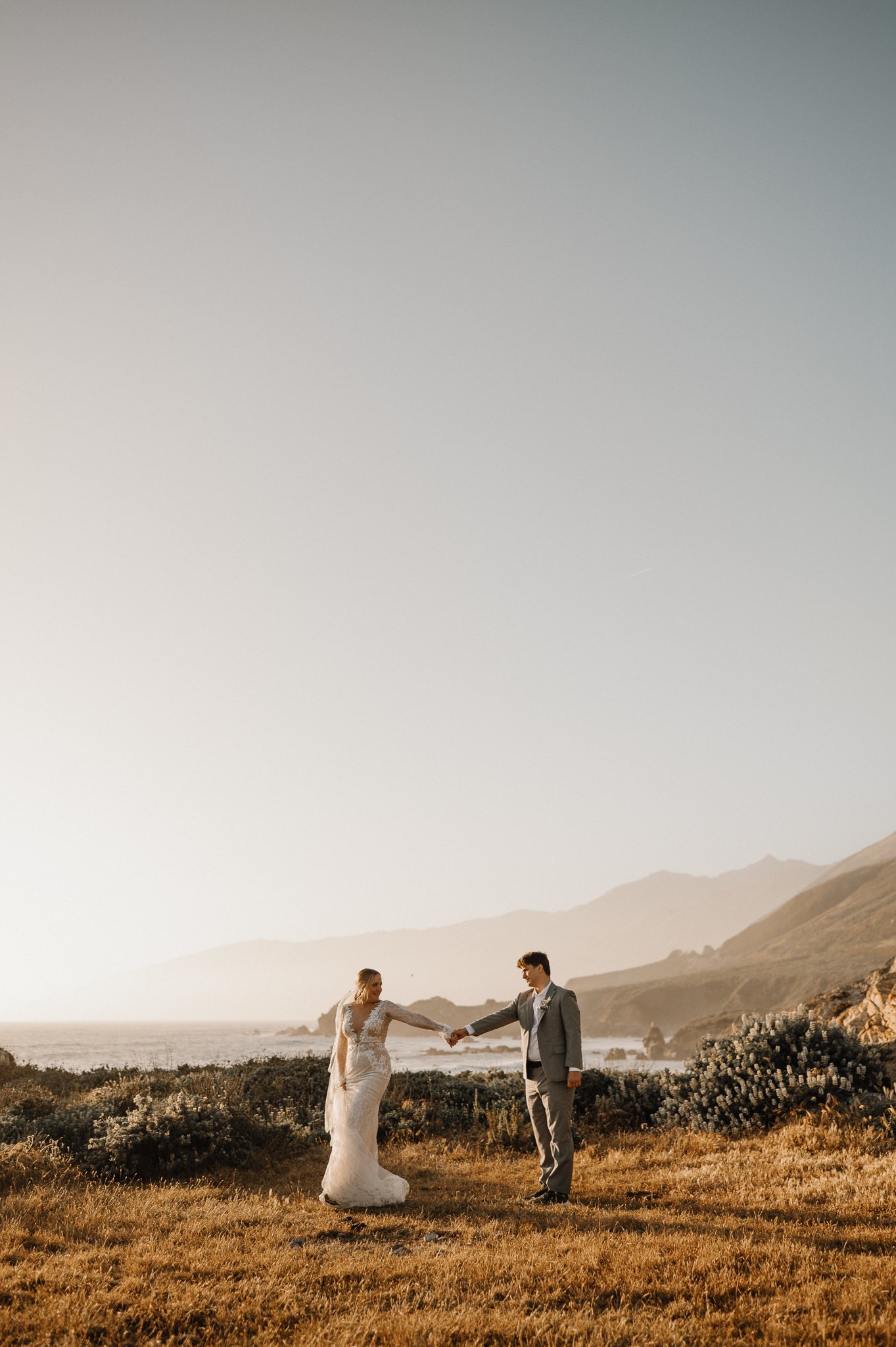 Big Sur Ventana wedding bride and groom walking in tall grass holding hands