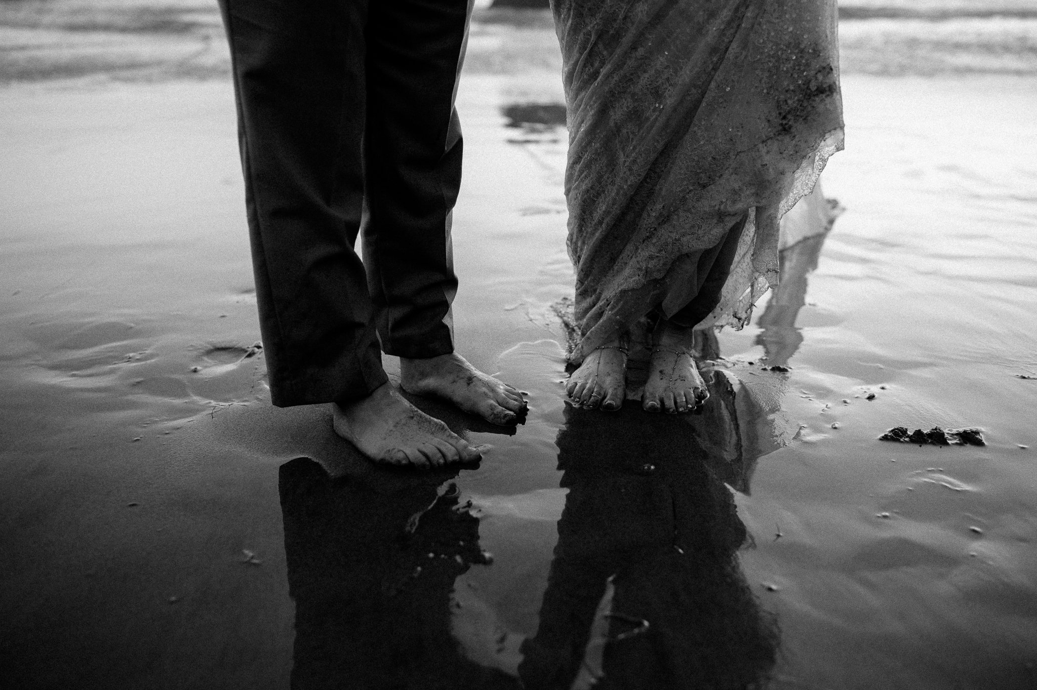 bride and grooms wet feet in sand on beach