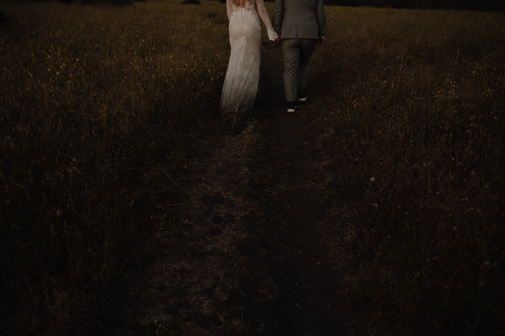 Big Sur Ventana wedding bride and groom walking holding hands up a hilly area through the grass