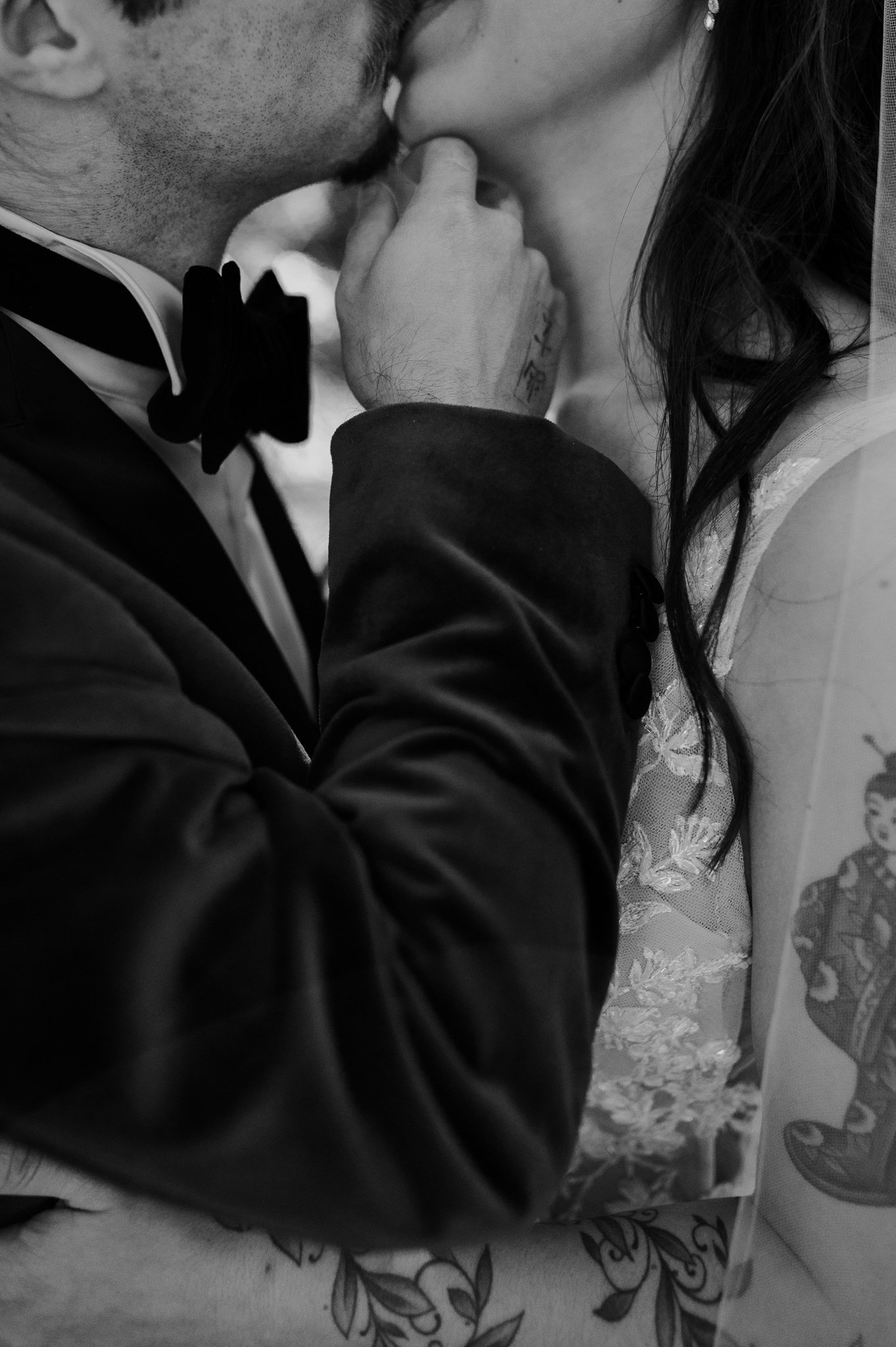 black and white close up of bride and grooms upper bodies kissing