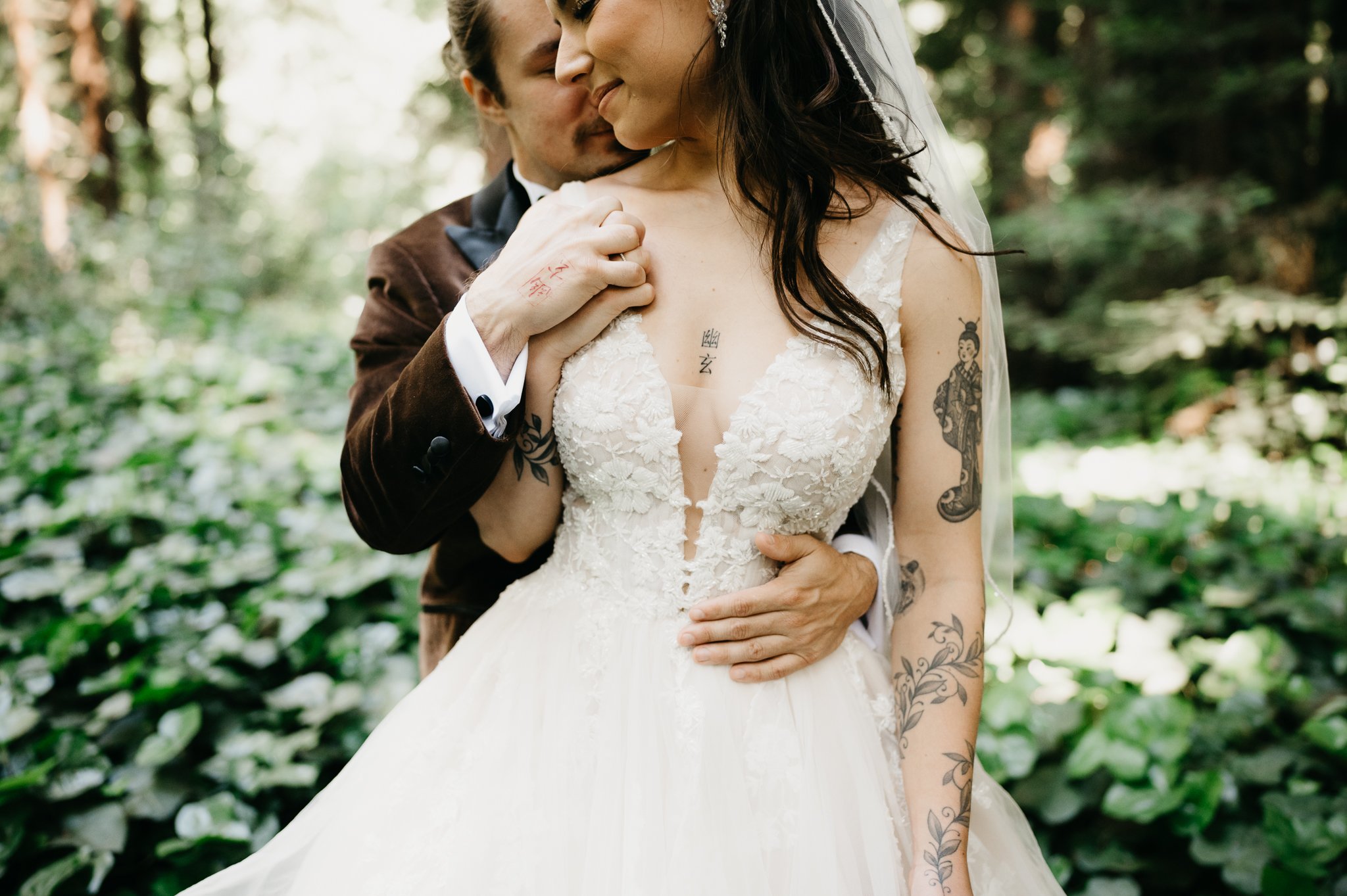 Big Sur Wedding groom standing behind bride kissing her shoulder as she glances back