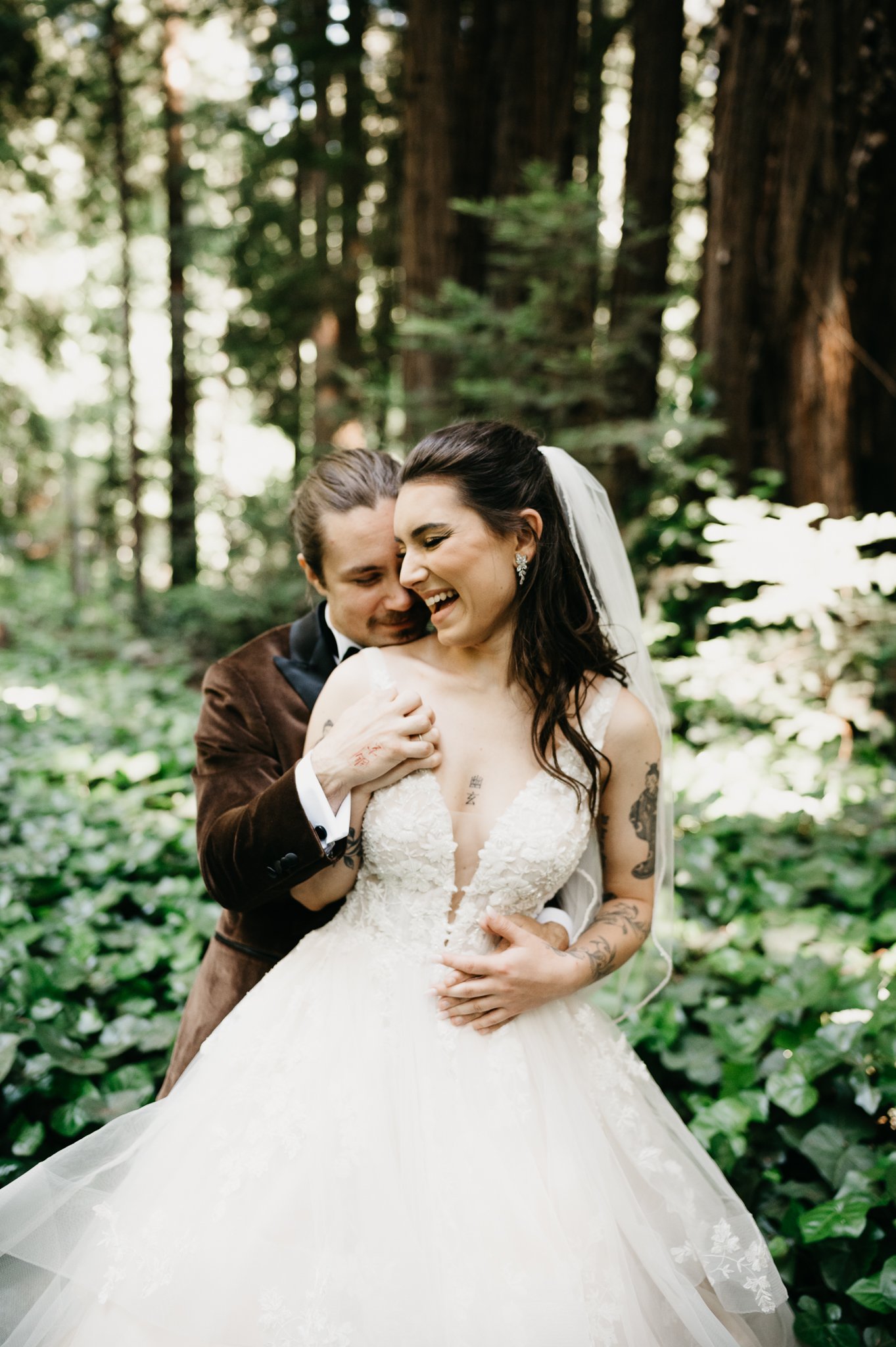 Big Sur Wedding groom standing behind bride kissing her shoulder as she glances back laughing
