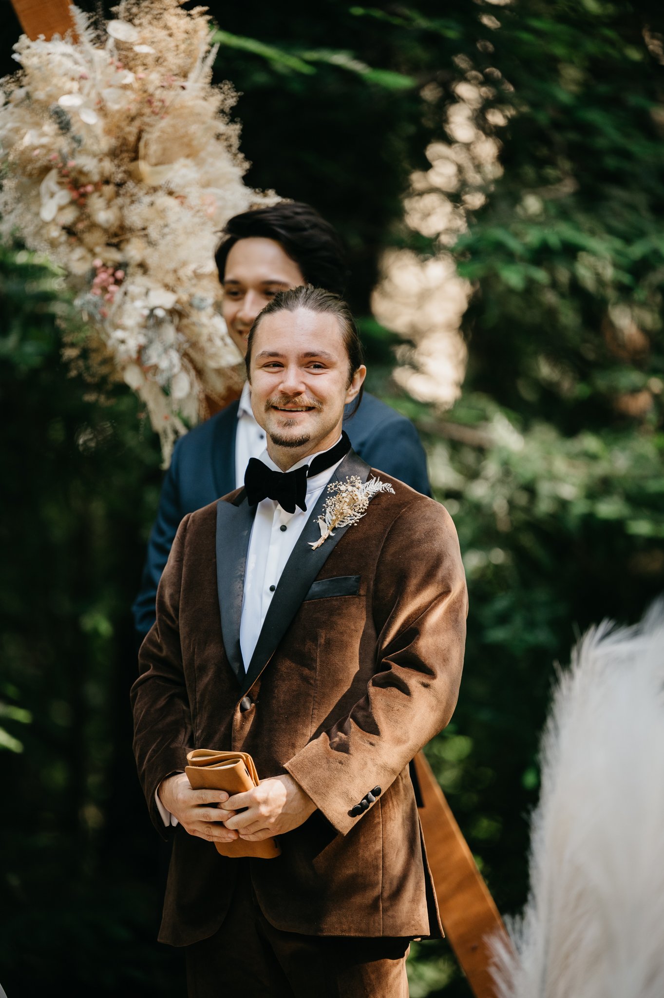 Big Sur Wedding ceremony groom in brown velvet suit waiting for bride at alter