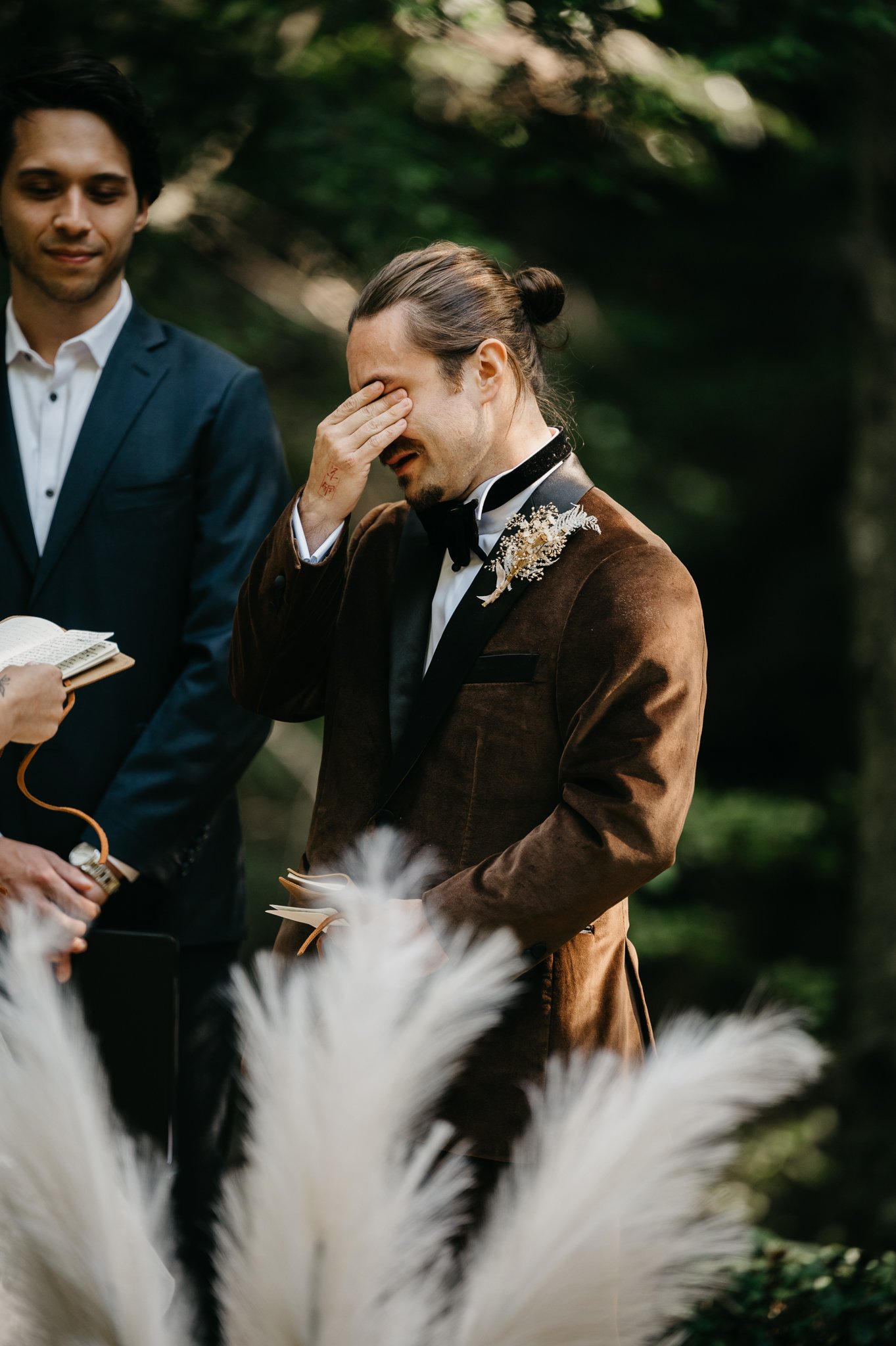 Glen Oaks wedding groom in brown velvet suit during ceremony tearing up 