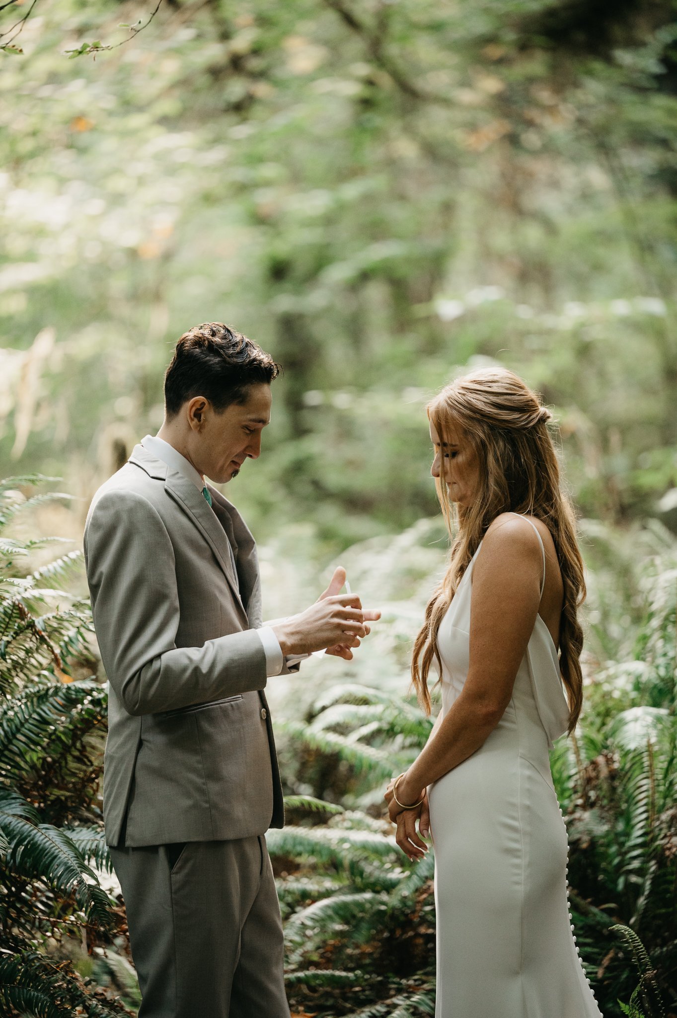 Bride and groom in wedding attire saying their vows among the tall redwood tress in Oregon