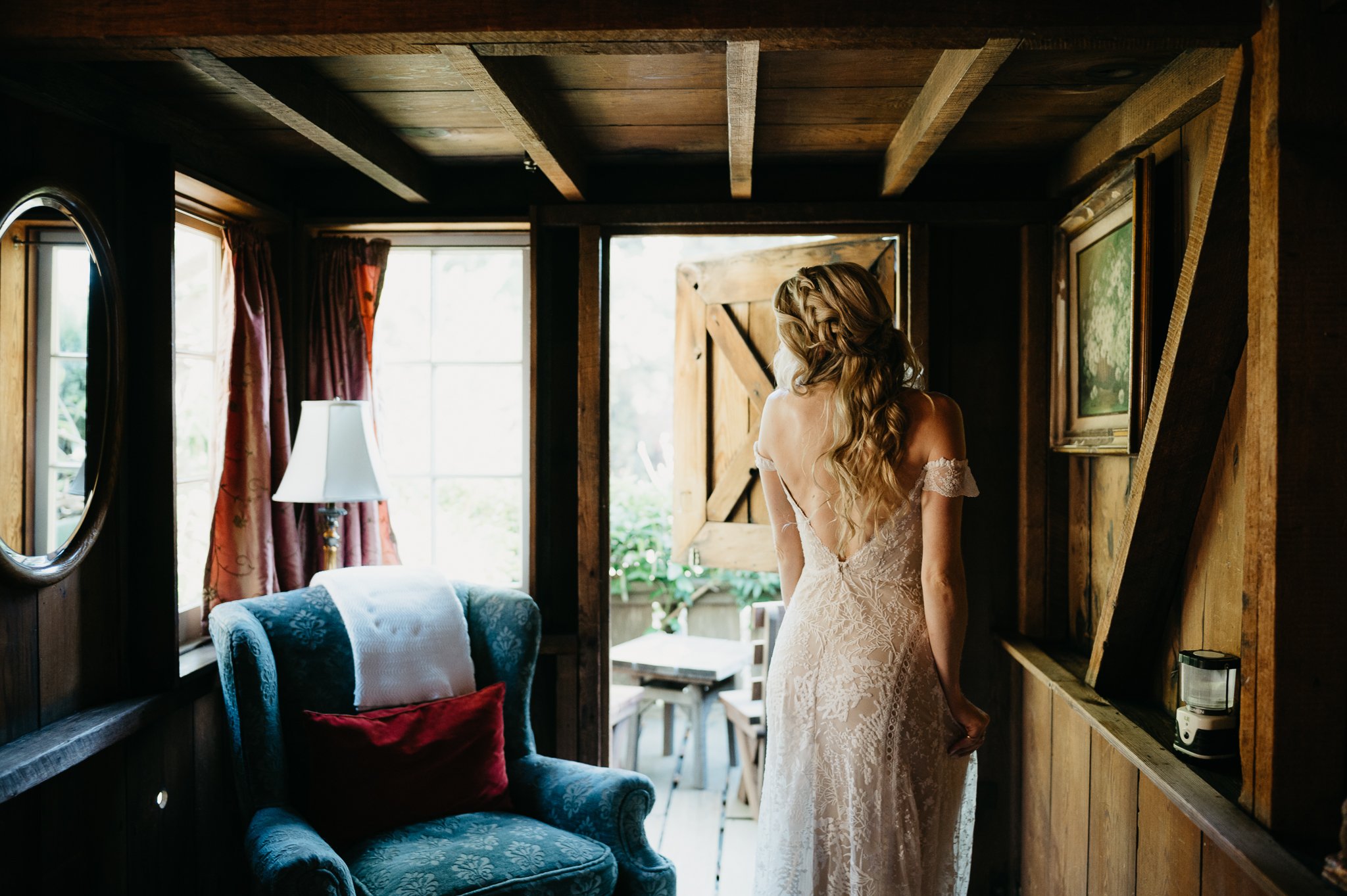 Bride getting ready for ceremony in wedding dress looking in mirror at Deetjen's Big Sur