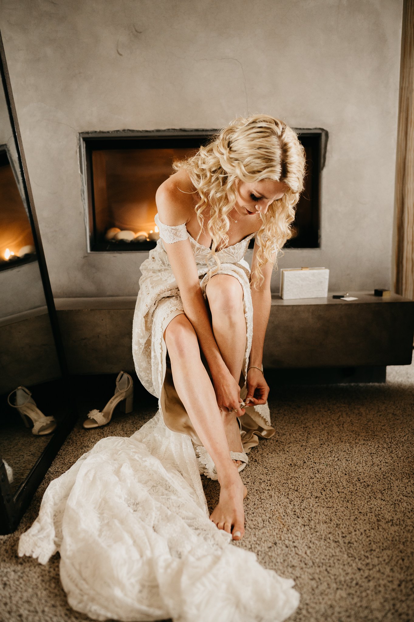 Bride at Wind and Sea Estate Big Sur, California in wedding dress putting on her shoes before ceremony