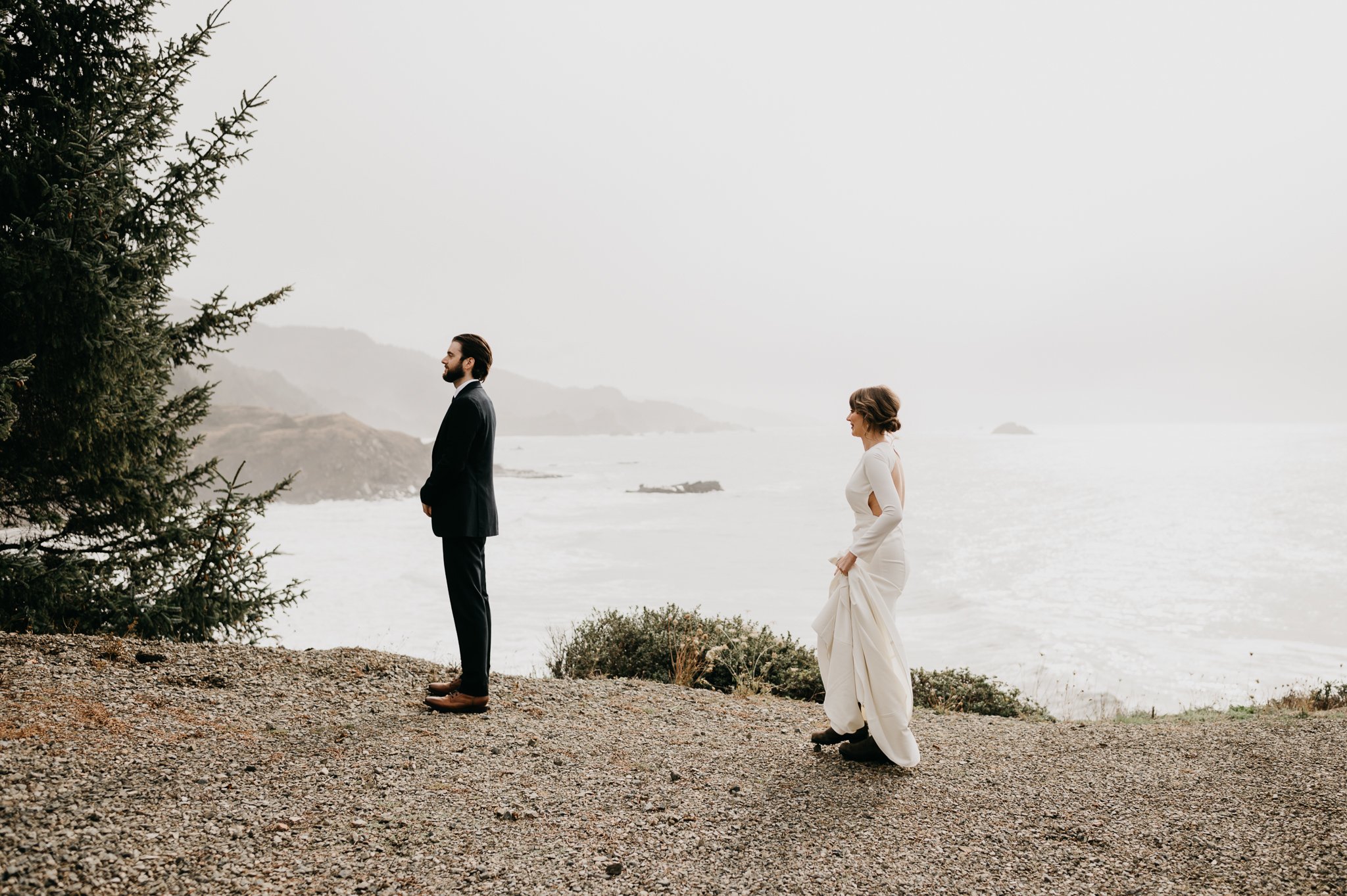 Bride and groom in wedding attire outside on a cliff overlooking the Pacific Ocean in Oregon doing their first Look!