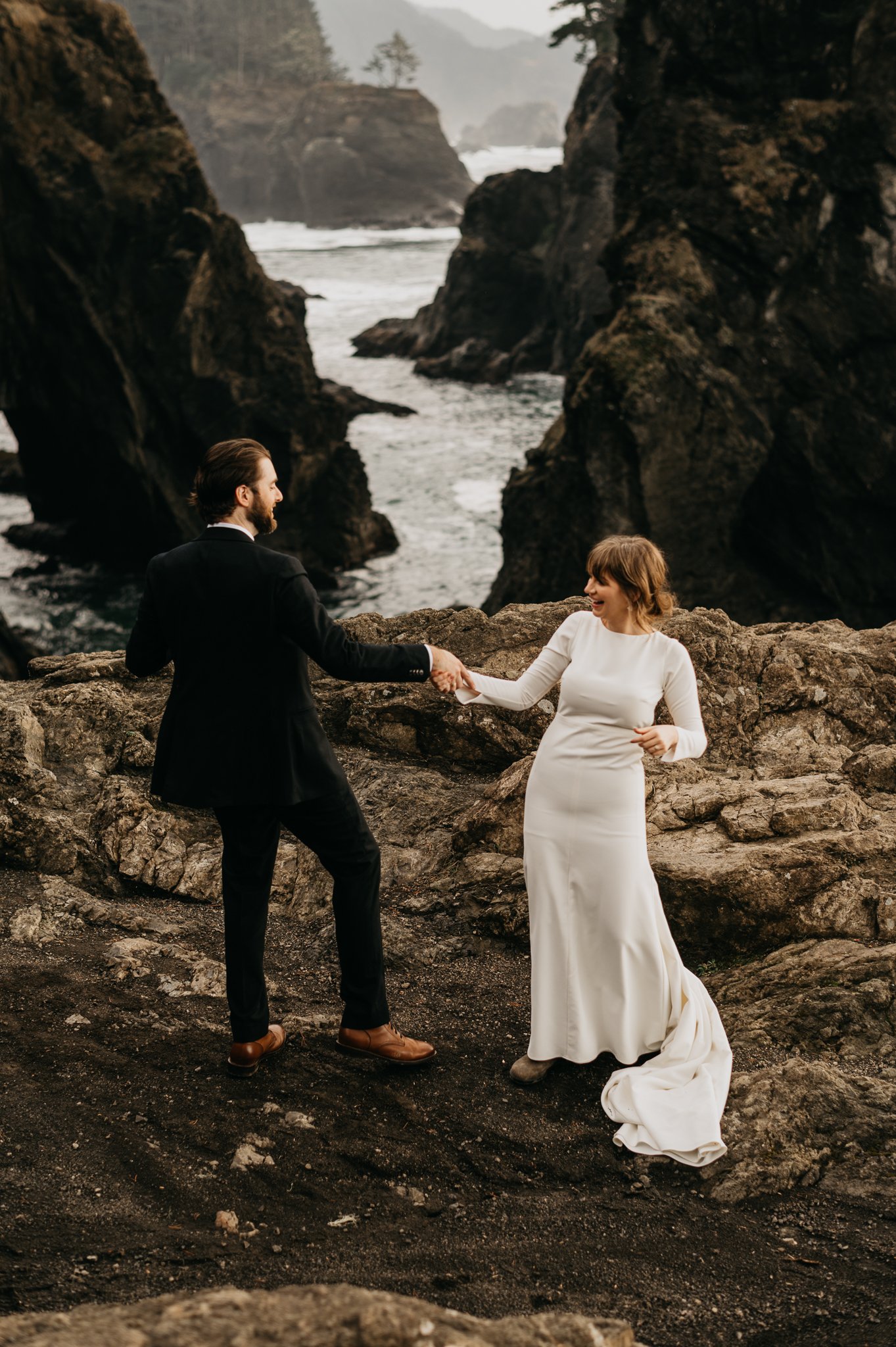 Bride and groom in wedding attire dancing on cliff with the cliffs and ocean in background