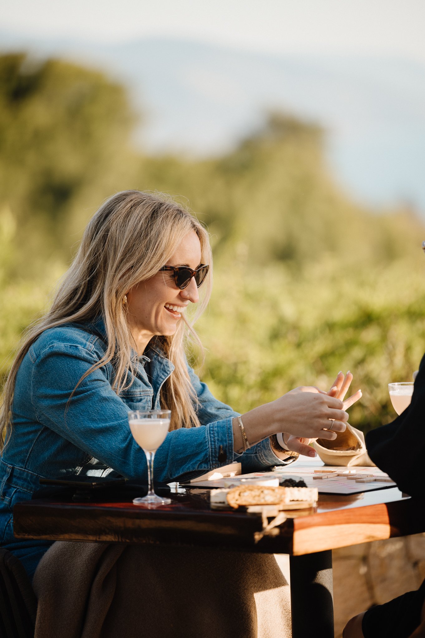  Newly engaged woman looking at her engagement ring while playing a game of Scabble at Ventana Big Sur. 