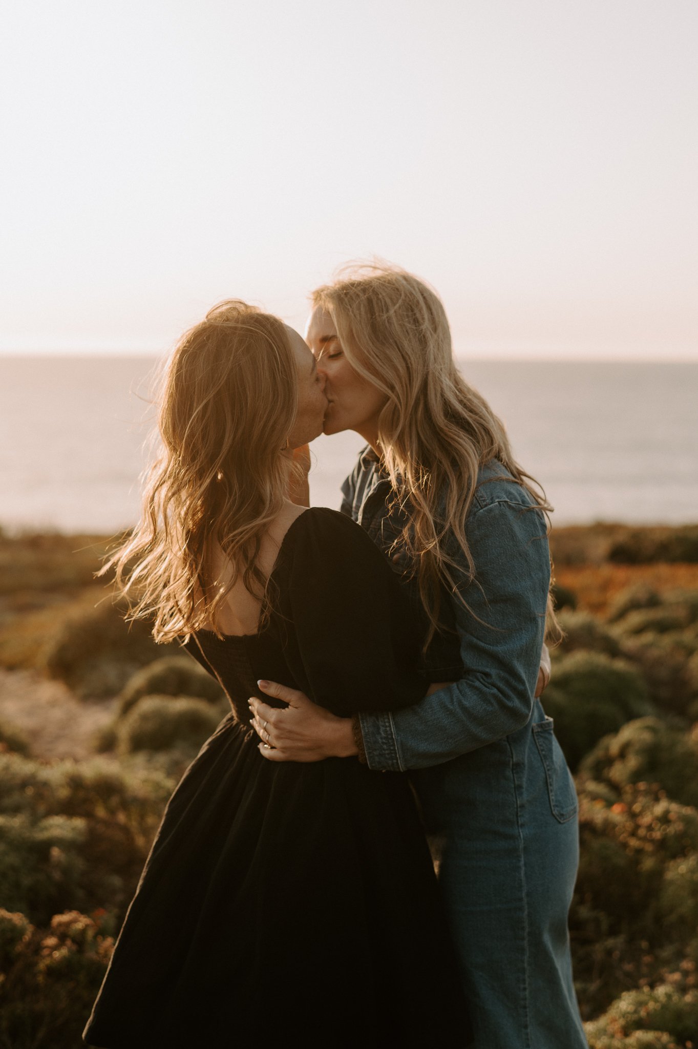  Newly engaged couple kissing on the cliffs at Big Sur overlooking the Pacific Ocean. 