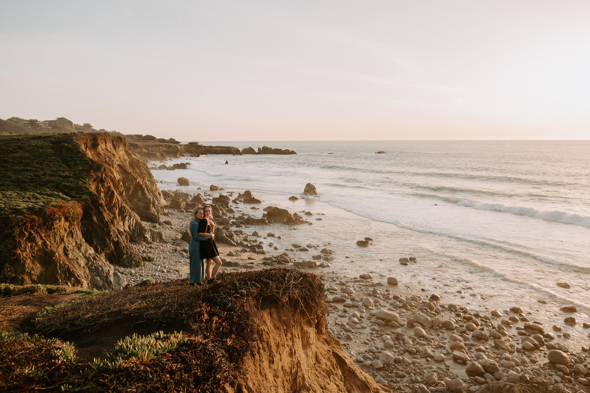  Newly engaged couple walking on cliffs overlooking Pacific Ocean in Big Sur, California 