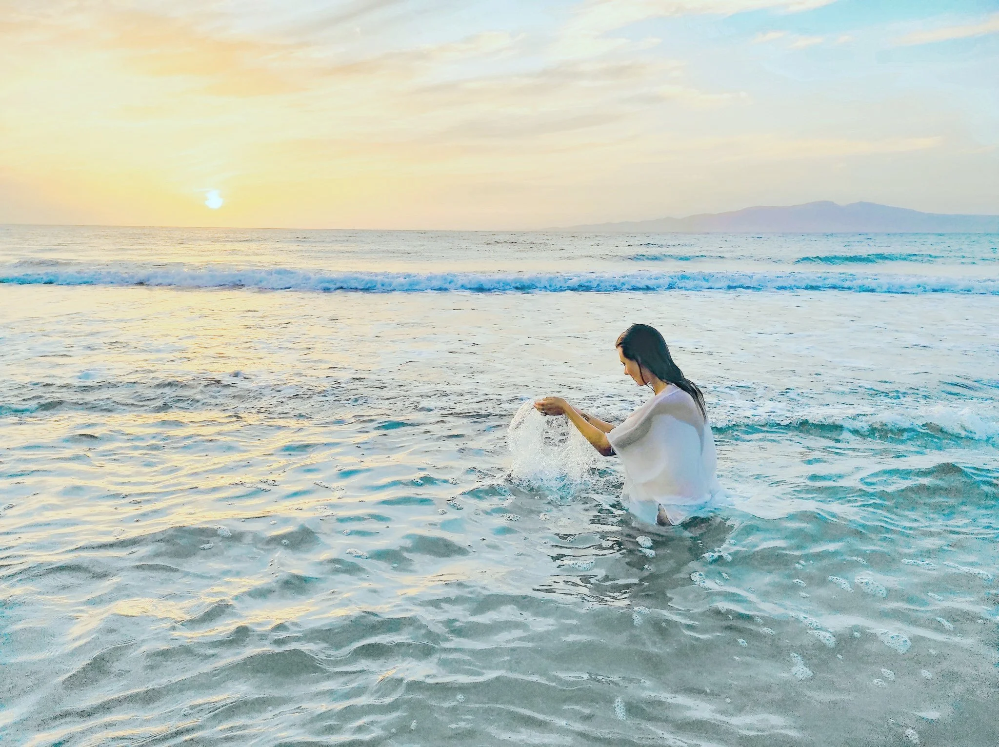Woman playing with water at the beach during sunset