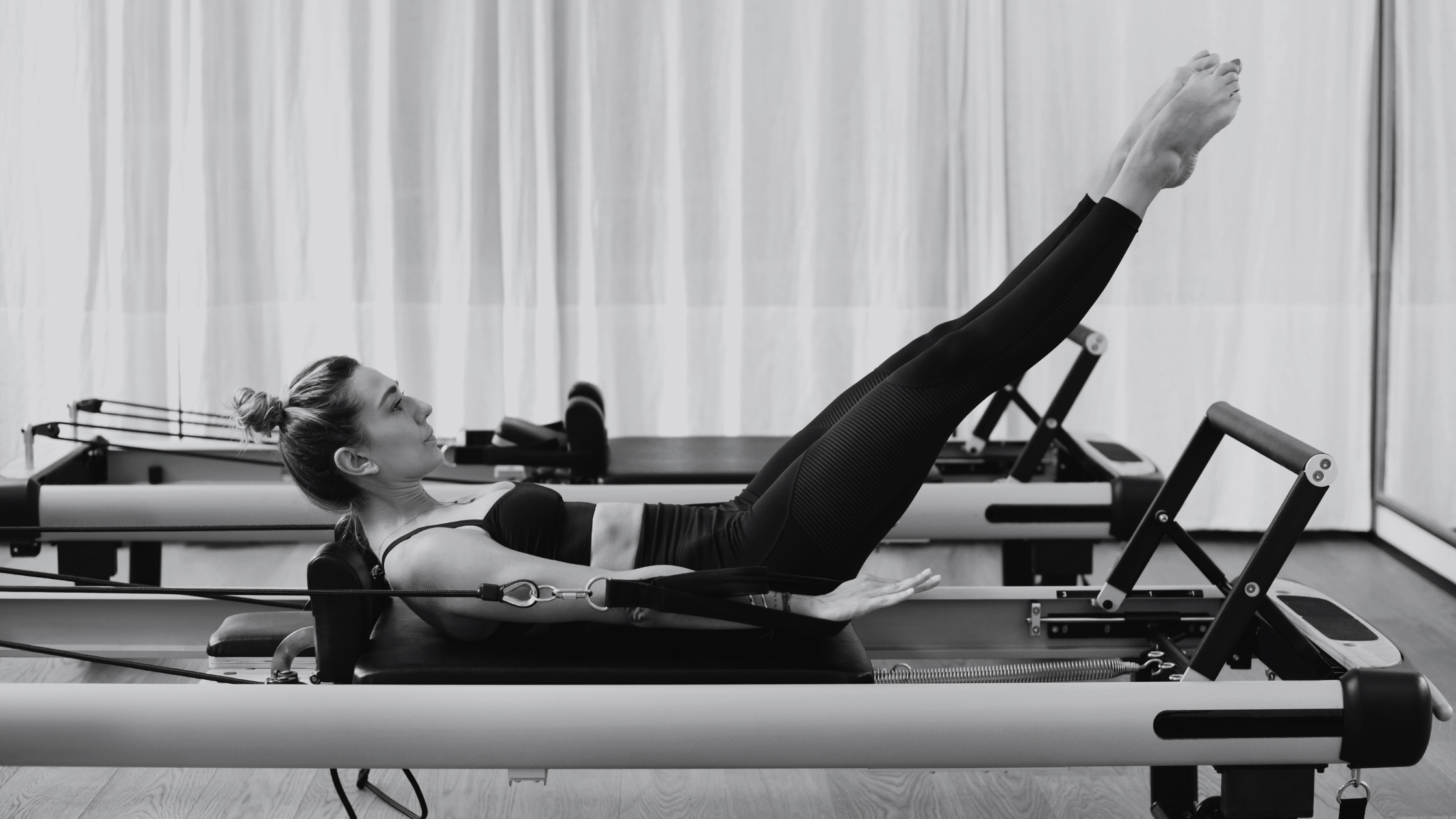 A person practicing doing reformer pilates in a pilates studio.