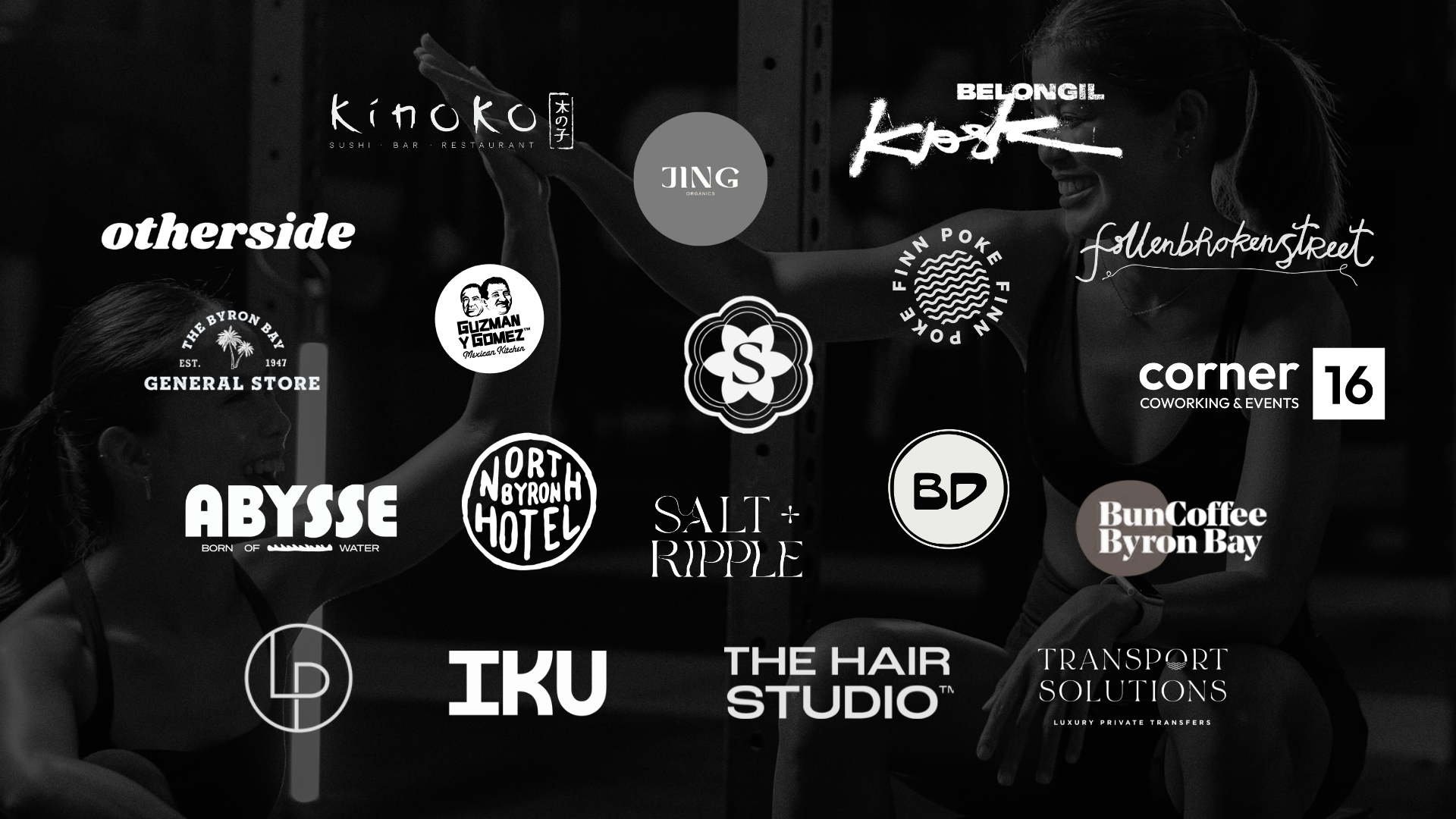 A black and white photo of two women high-fiving, surrounded by various logos and business names for local businesses and organizations, including Kinoko, Belongil Koak, JING Organics, general store, Guzman y Gomez, salty ripple, corner 16 coworking events, Bun Coffee Byron Bay, Abyss, North Byron Hotel, LD, IKU, The Hair Studio, Transport Solutions, and others.