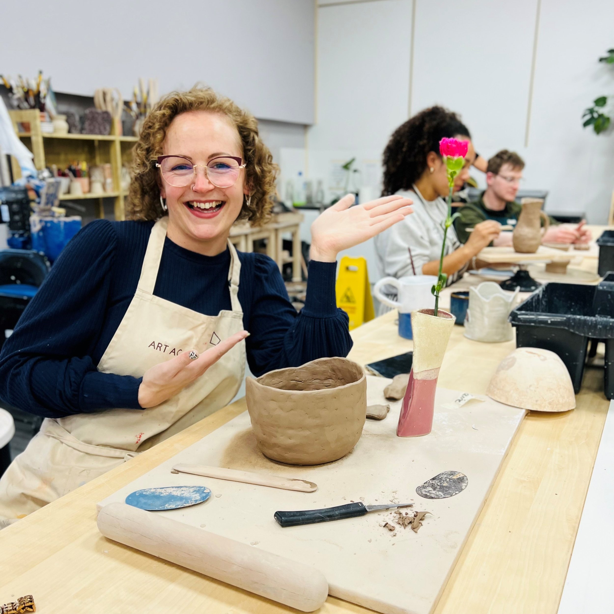Pottery student smiles about her clay creation