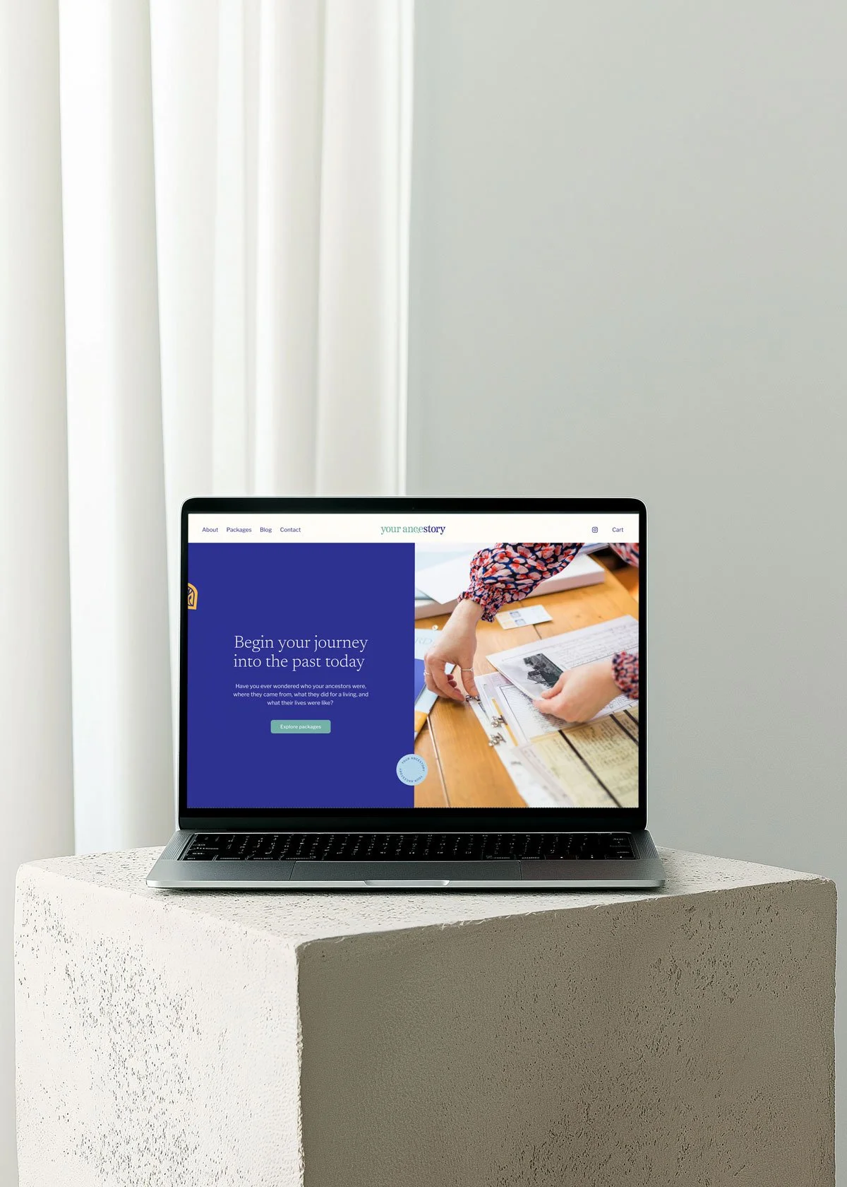 Laptop displaying a website about genealogy and ancestry research, placed on a textured white pedestal near a window with white curtains.