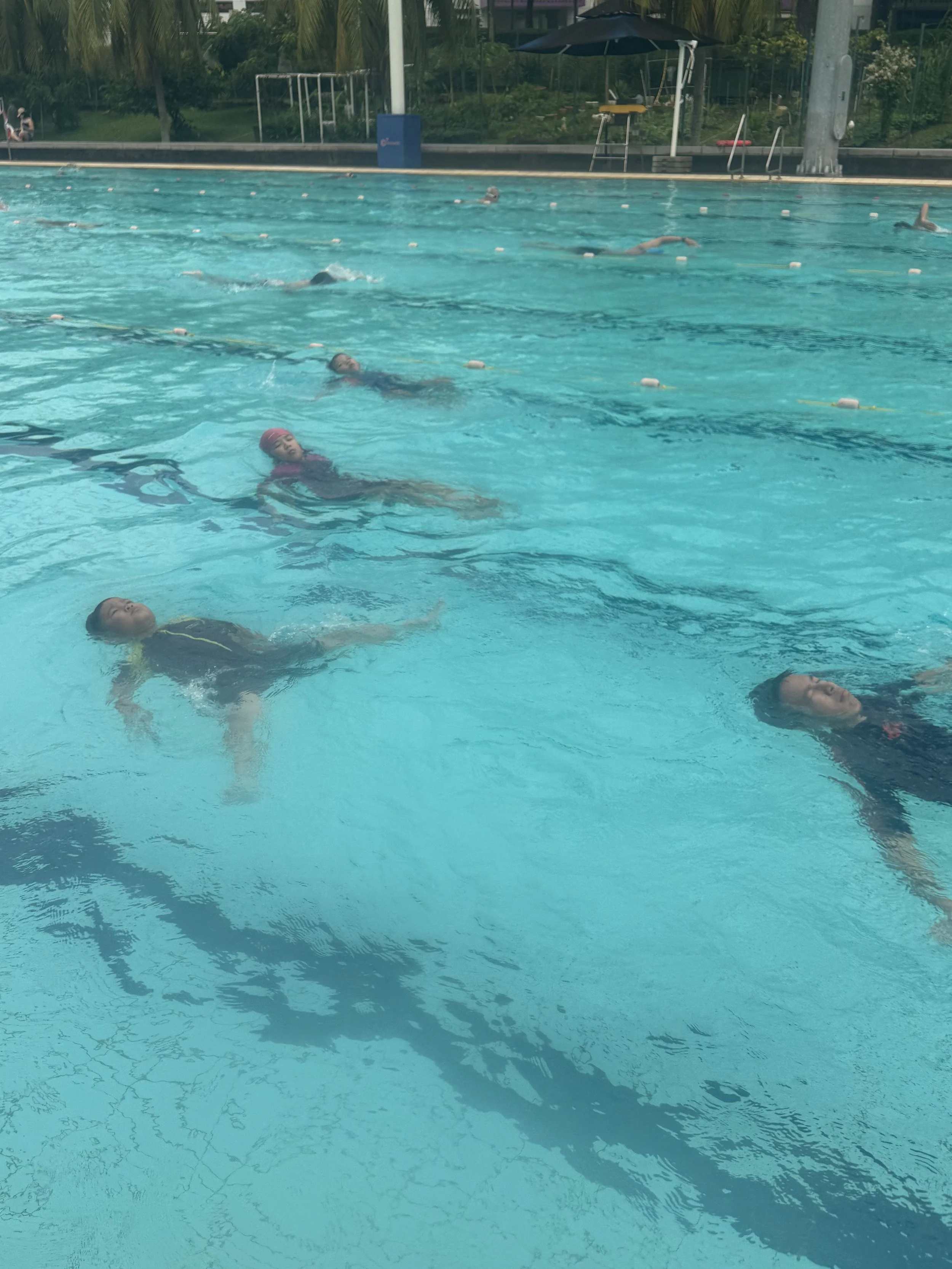 Swimmers practicing in an outdoor swimming pool during daytime