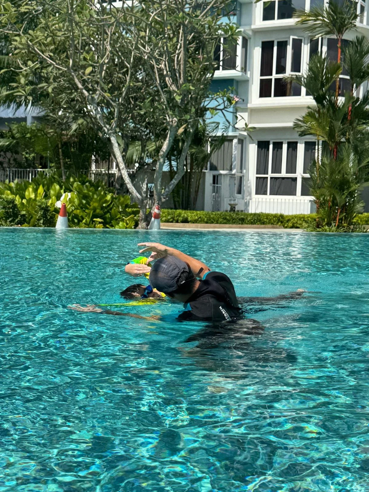 Swim coach helping a child improve body position and swimming coordination