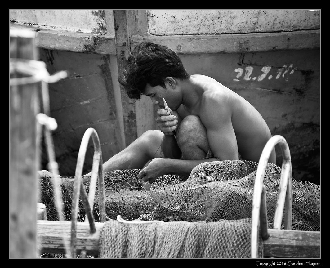 Ropang Ropov Fishing Village, On the road east from Sihanoukville, Cambodia --
Fisherman at work, repairing the net.