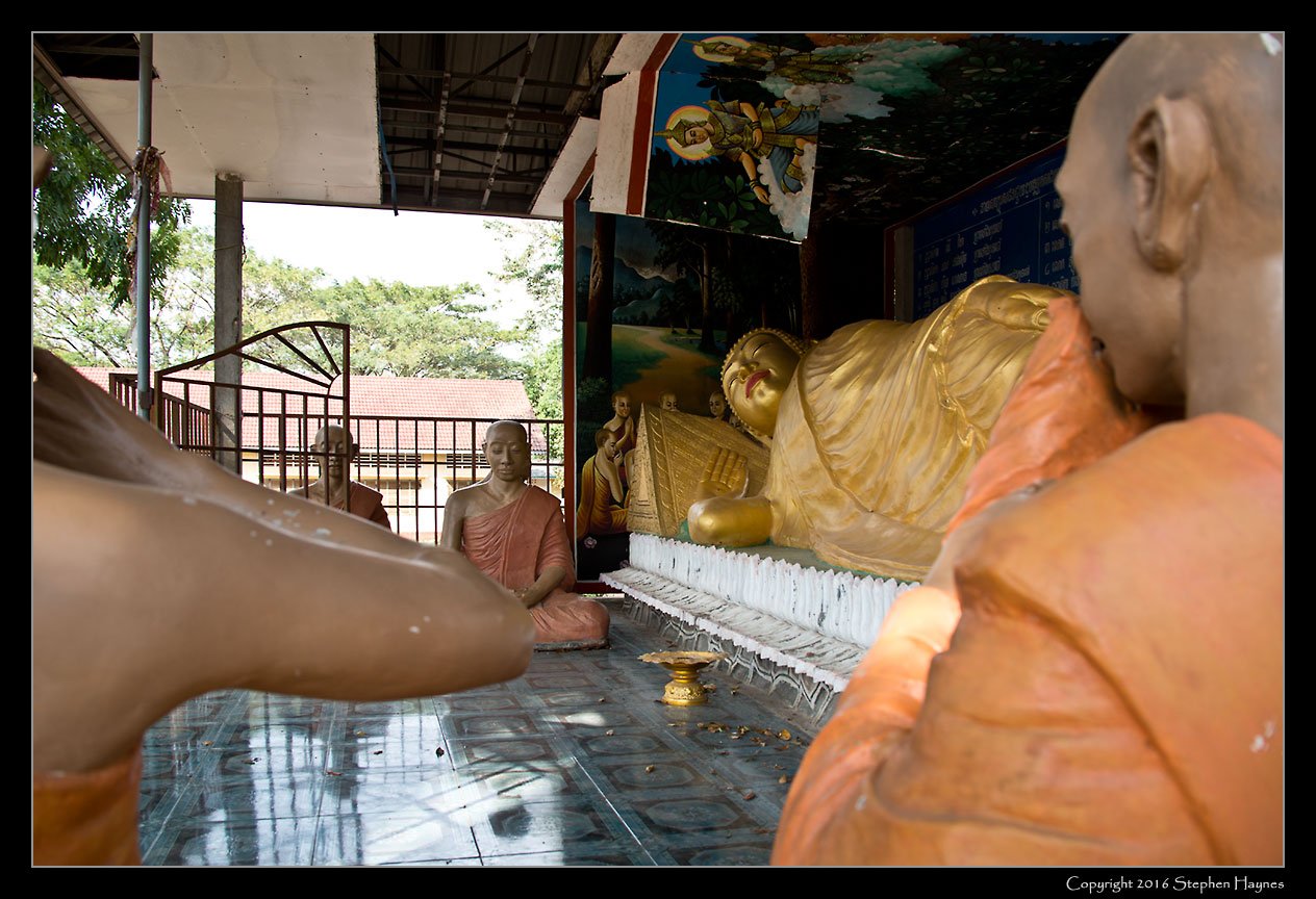 Sovann Kongkea Pagoda, On the road east from Sihanoukville, Cambodia --
We saw nowhere else effigies of praying monks associated with a Buddha-figure. (Note
the missing and damaged ceiling tiles; the entire Pagoda grounds had a certain
run-down lo