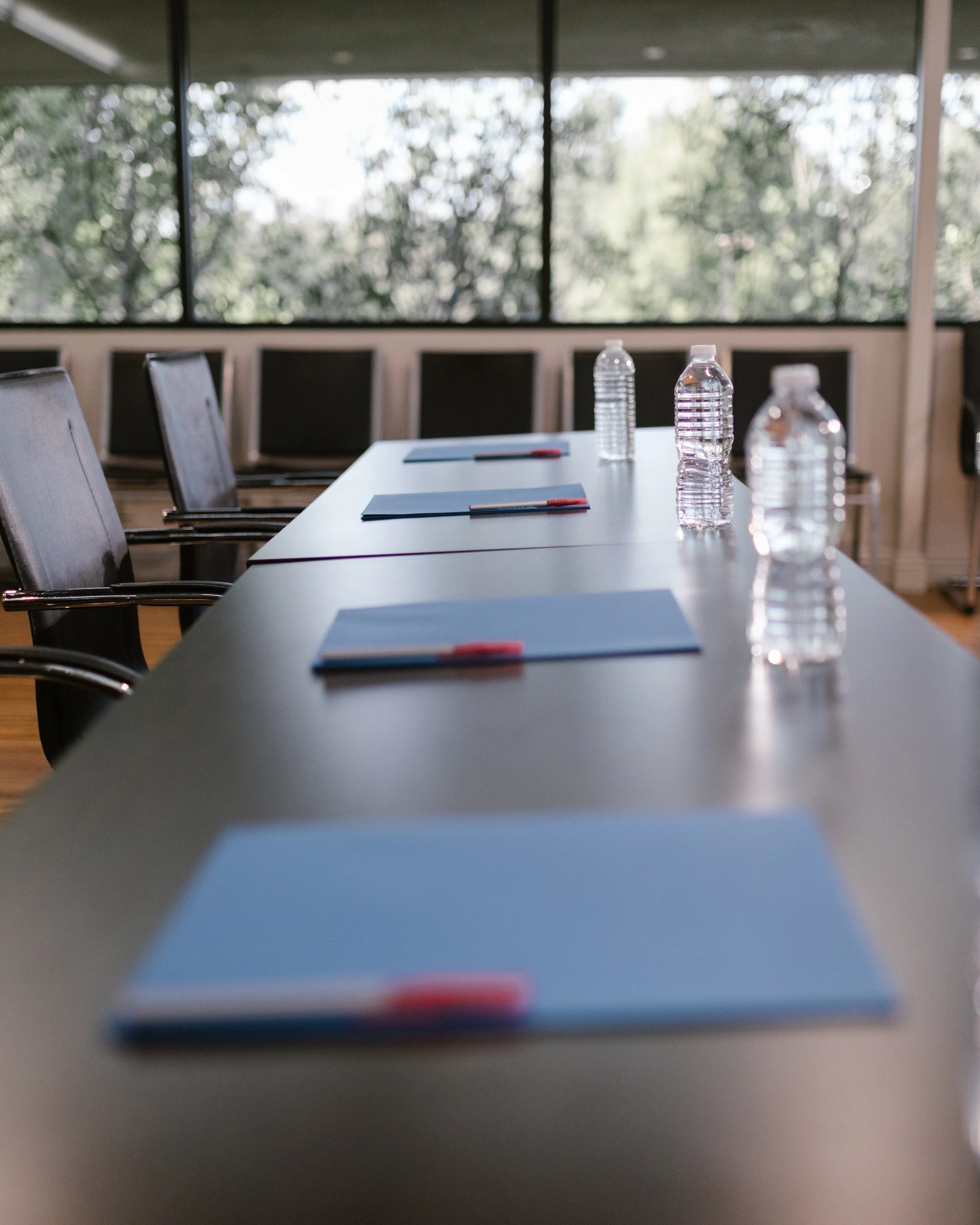 Empty conference room prepared for a business speaking engagement with folders and water bottles on the meeting table.