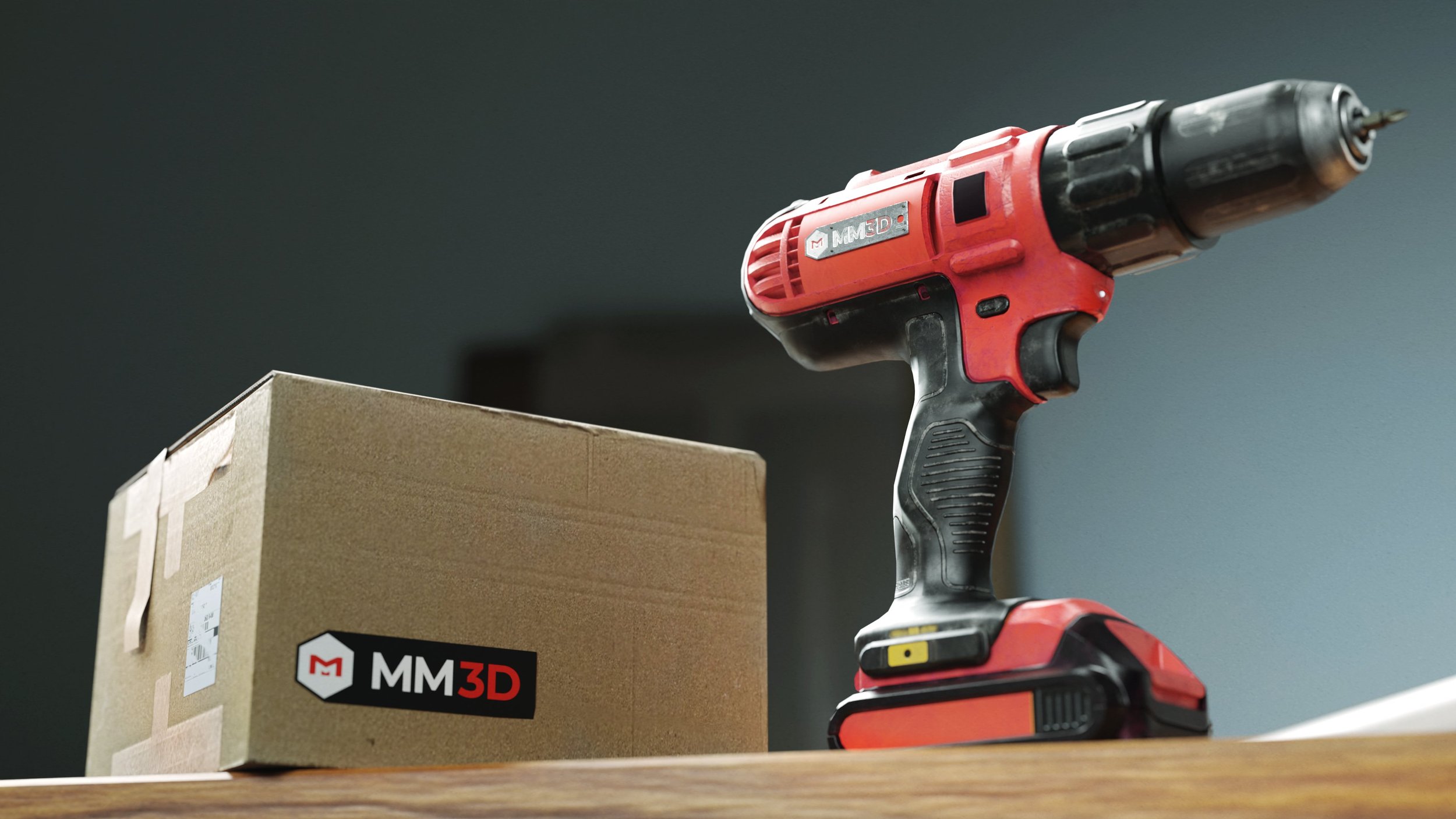A cordless red and black power drill is resting on a wooden surface next to a cardboard box with an MM3D logo.