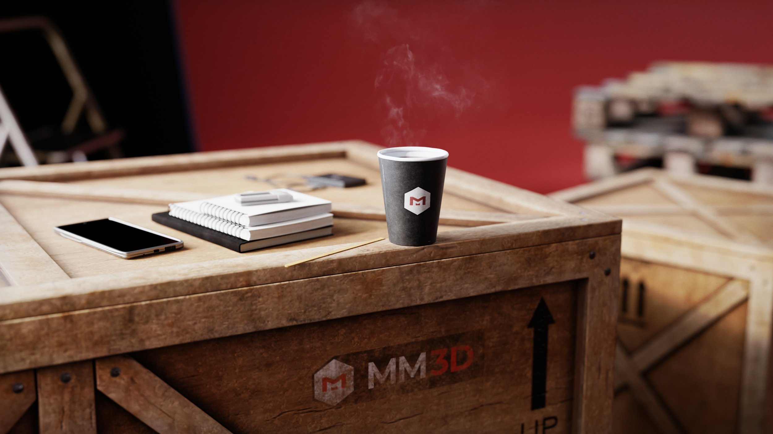 A wooden table with notebooks, a pen, a smartphone, and a steaming coffee cup with a logo, against a red wall and stacked crates in the background.