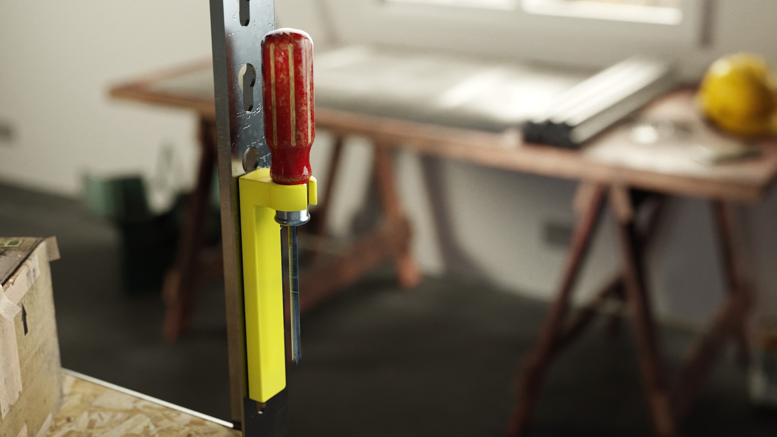 Close-up of a woodworking clamp with a red handle and yellow body, attached to a metal frame, in a workshop.
