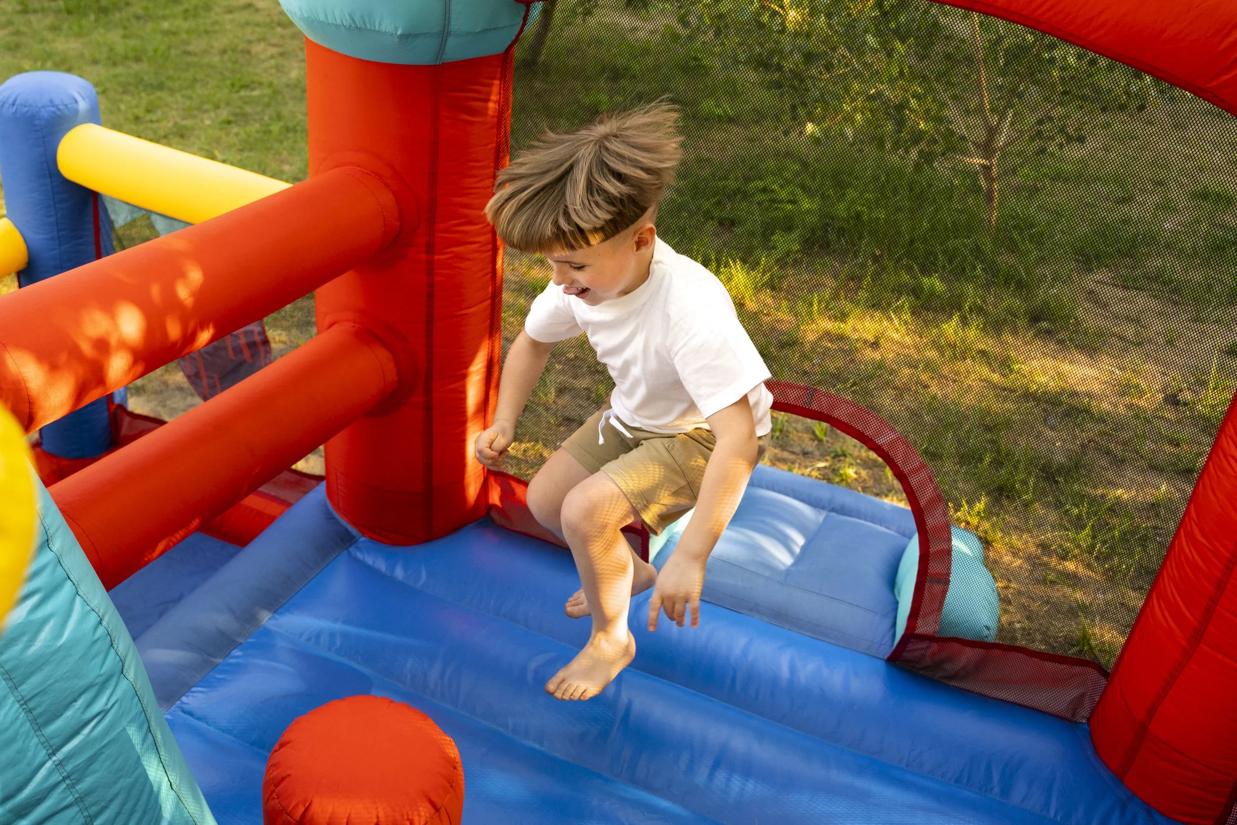 Child playing on an inflatable bounce house outdoors.